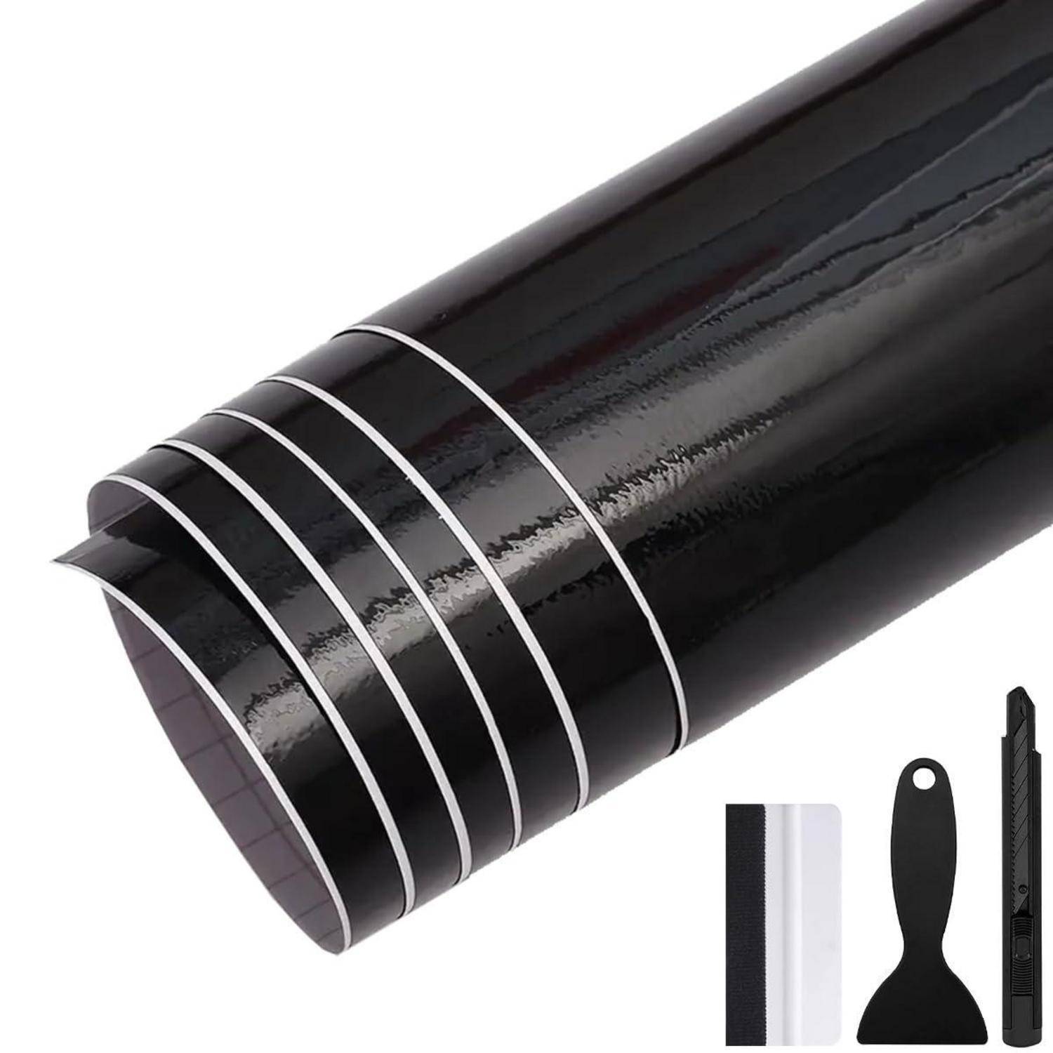 Schwarze glänzende Rolle mit selbstklebendem Folienmaterial mit weißen Führungsstreifen, gezeigt mit einem Rakel, Schaber und Cutter.