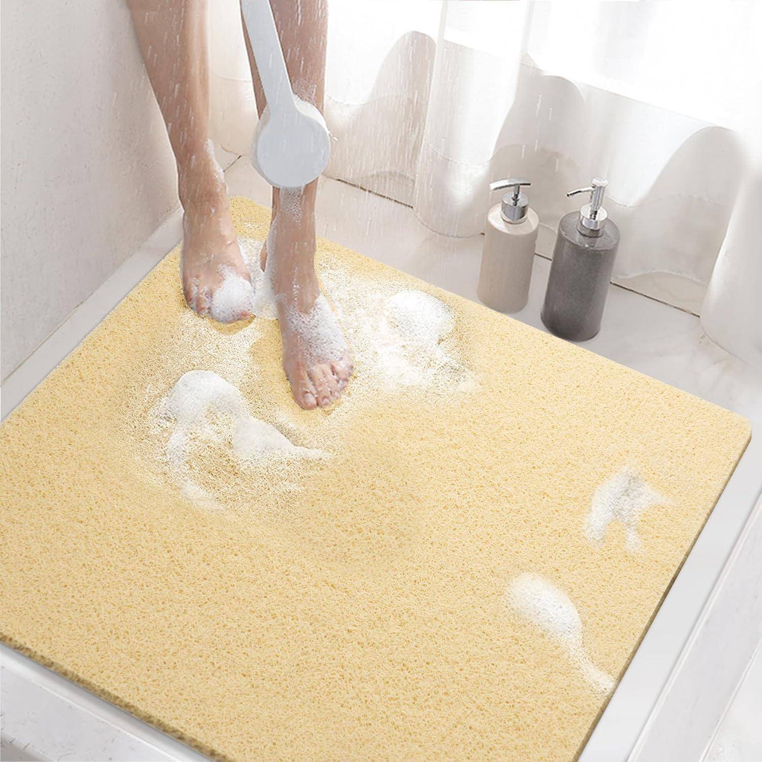 Person, die Seife von ihren Füßen auf einer gelben rutschfesten Badewannenmatte unter der Dusche im Badezimmer abspült.