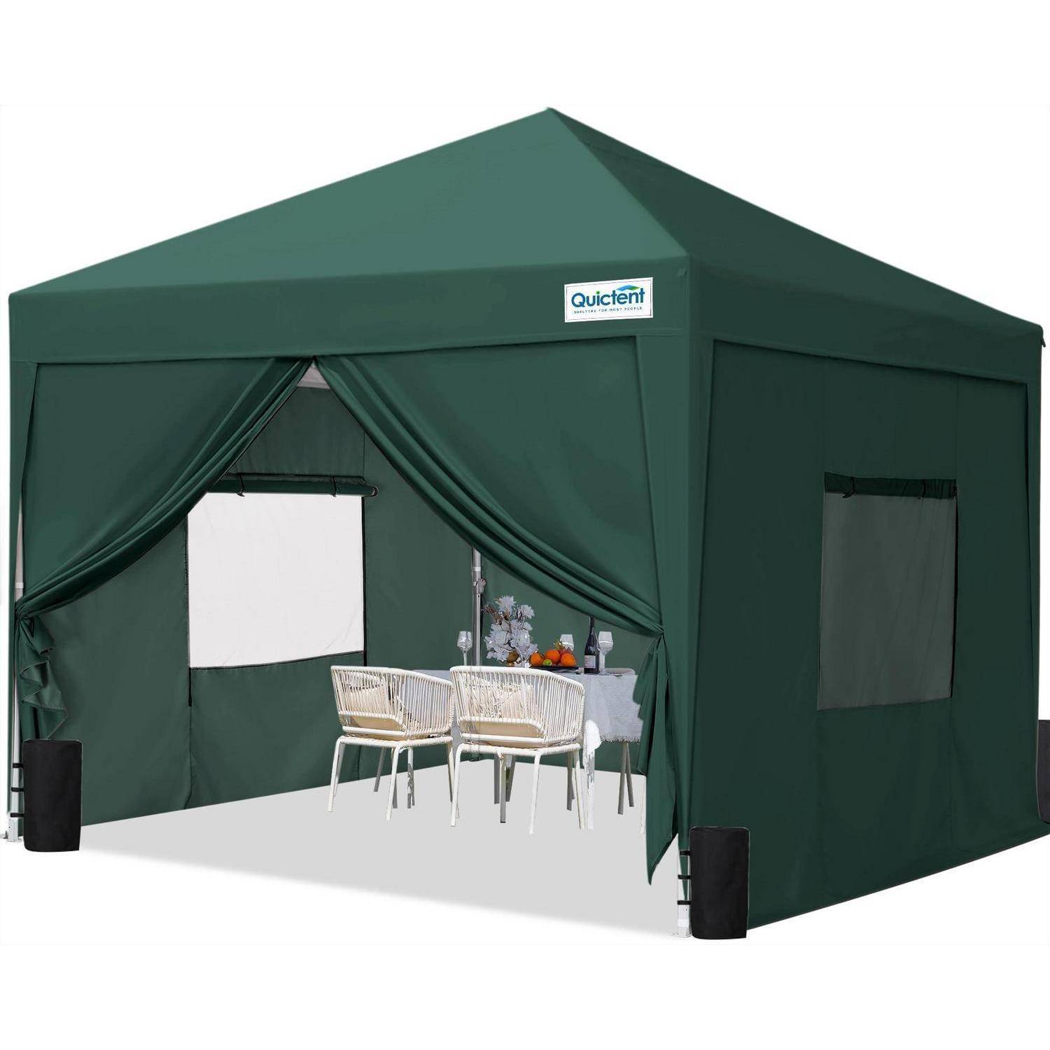 Dunkelgrünes Outdoor-Pavillon-Zelt mit offenen vorderen Vorhängen, einem kleinen Tisch und zwei Stühlen im Inneren