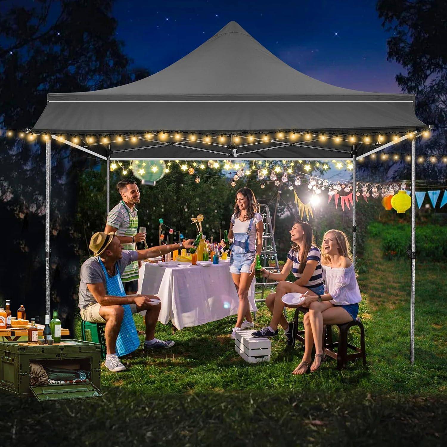 Freunde unterhalten sich auf einer nächtlichen Außenparty unter einem beleuchteten Baldachindach mit Getränken, einem Tisch und Lichterketten in einem Grasbereich.