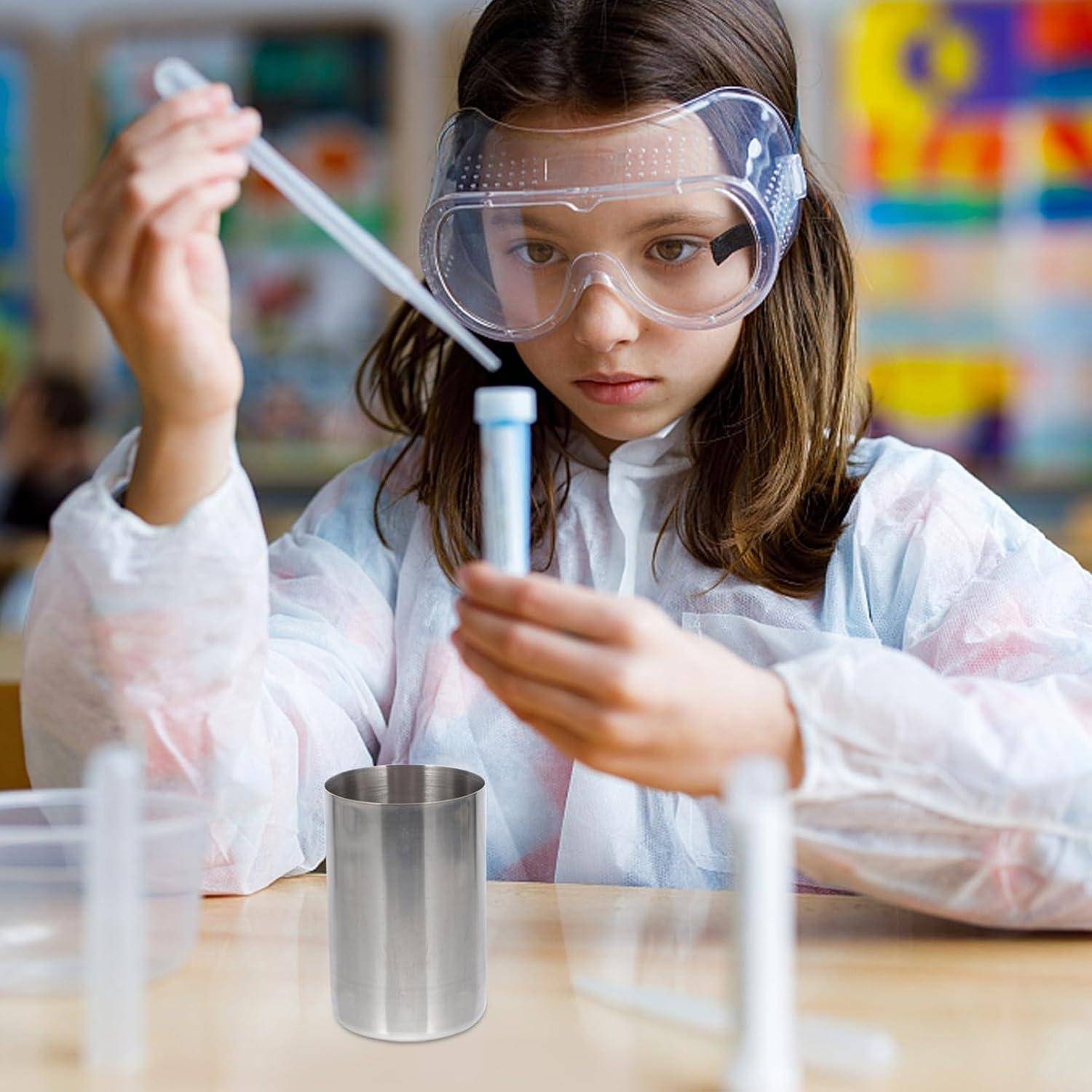 Junges Mädchen in Schutzbrille und Laborkittel verwendet während eines Wissenschaftsexperiments an einem Tisch sorgfältig eine Pipette und ein Reagenzglas.