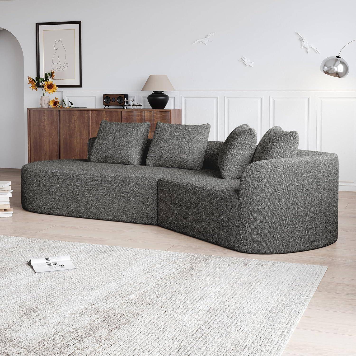 Modernes graues modulares Ecksofa in einem hellen minimalistische Wohnzimmer mit Schrank, Lampe, Wandkunst und hellem Teppich.