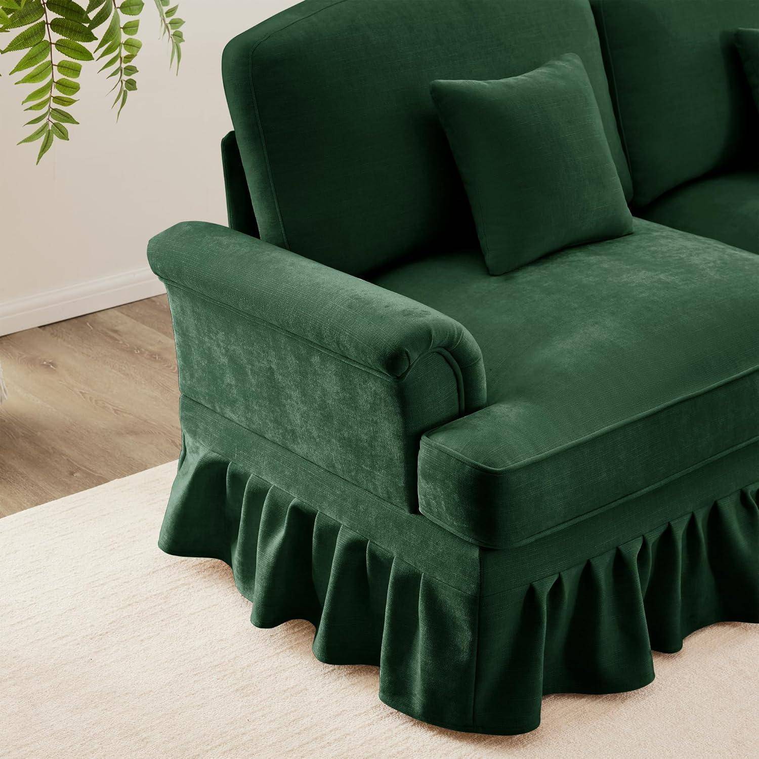 Dunkelgrünes Samtsofa mit gekräuseltem Sockel und passendem Kissen in einem minimalistischen Raum mit hellem Holzboden und hellem Teppich.