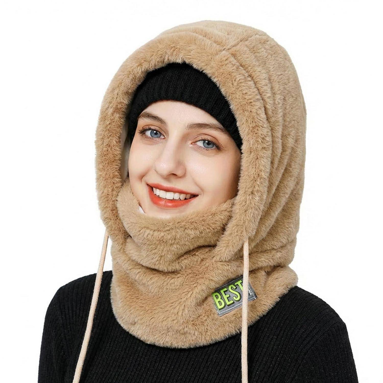 Lächelnde Frau, die eine beige Kunstfellkapuze und einen Halswärmer mit einem schwarzen Hut und Pullover vor weißem Hintergrund trägt.