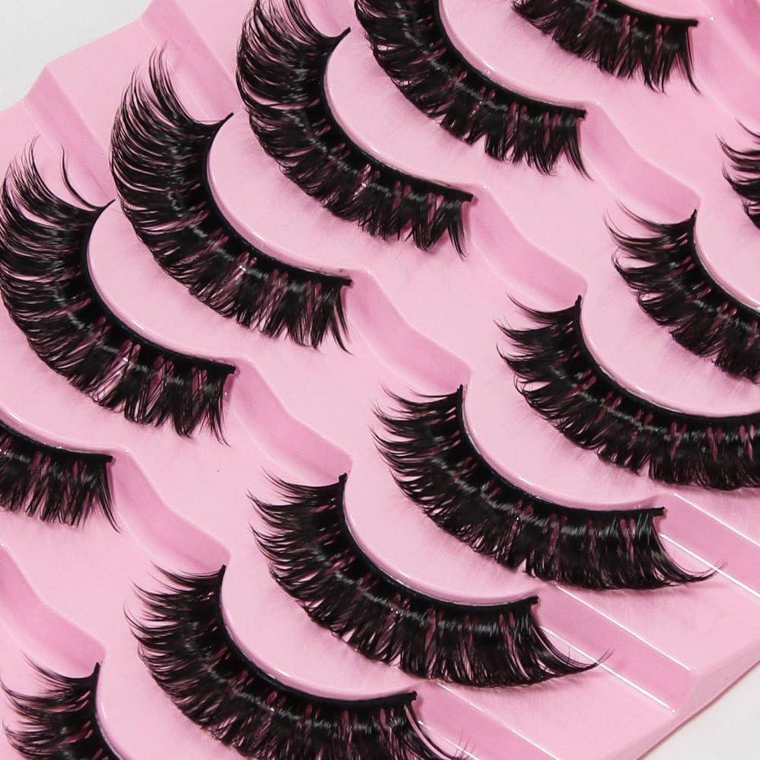 Sortierte schwarze künstliche Wimpern in Reihen auf rosa Verpackungstabletts angeordnet.
