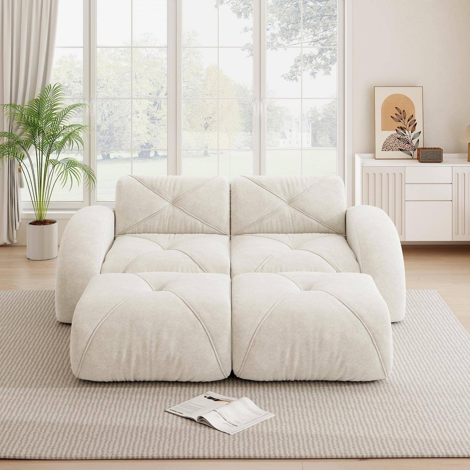 Weiches weißes modulares Sofa in einem hellen Wohnzimmer mit großen Fenstern, einer Topfpflanze, einem Sideboard und einer offenen Zeitschrift auf einem gestreiften Teppich.