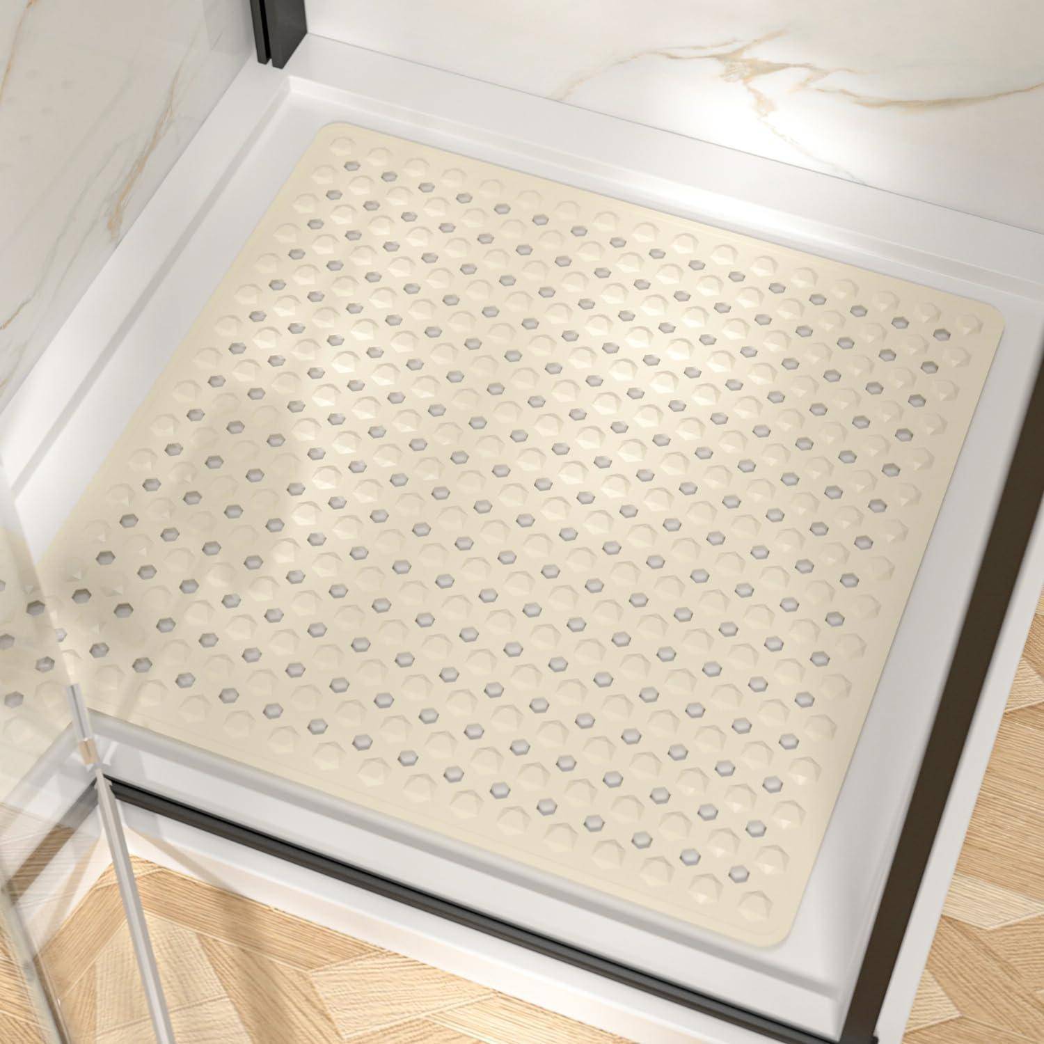 Eine quadratische beige rutschfeste Matte mit erhabenen Saugnapfnoppen sitzt in einem weißen Dusch- oder Badewannenboden.
