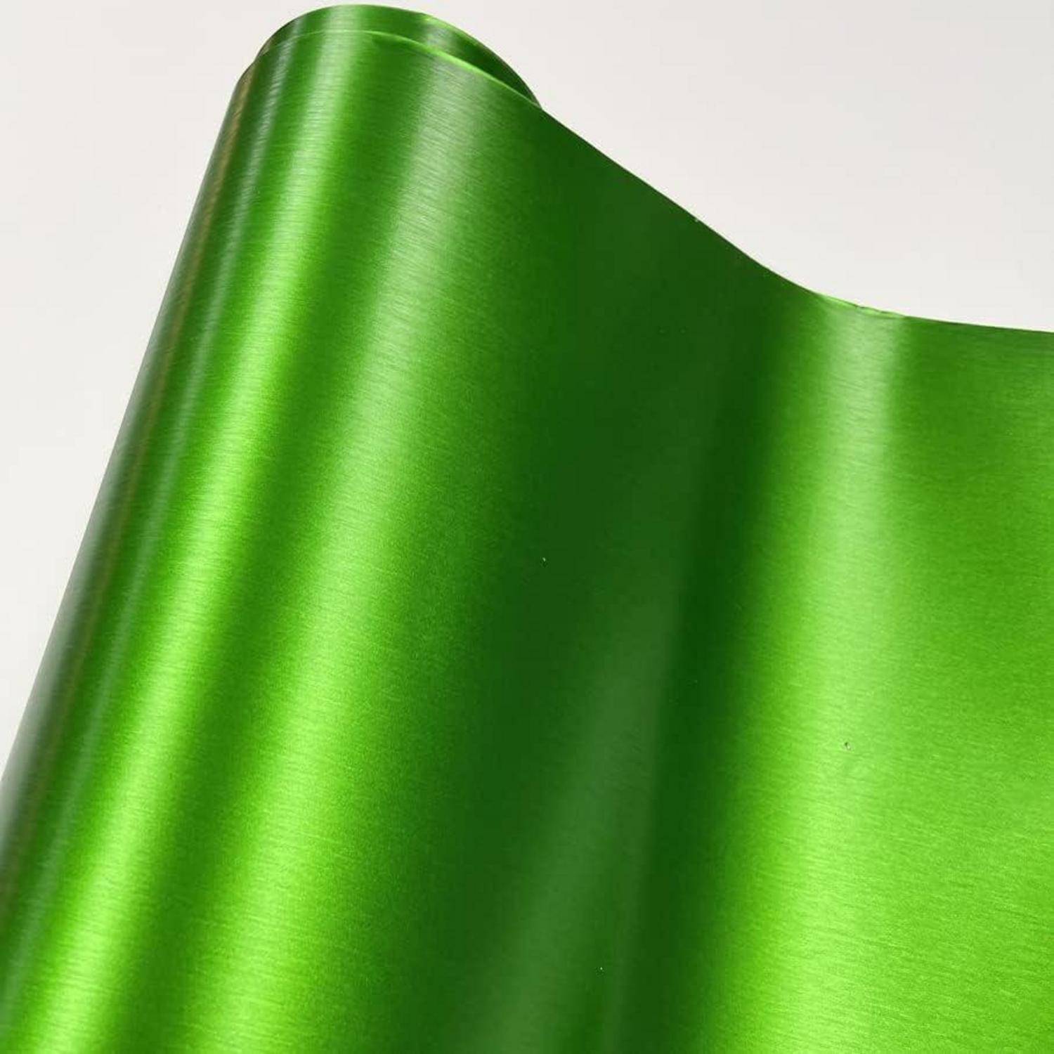 Nahaufnahme von glänzendem metallischem grünem Satinstoff mit glatten gefalteten Wellen auf einfachem hellem Hintergrund.