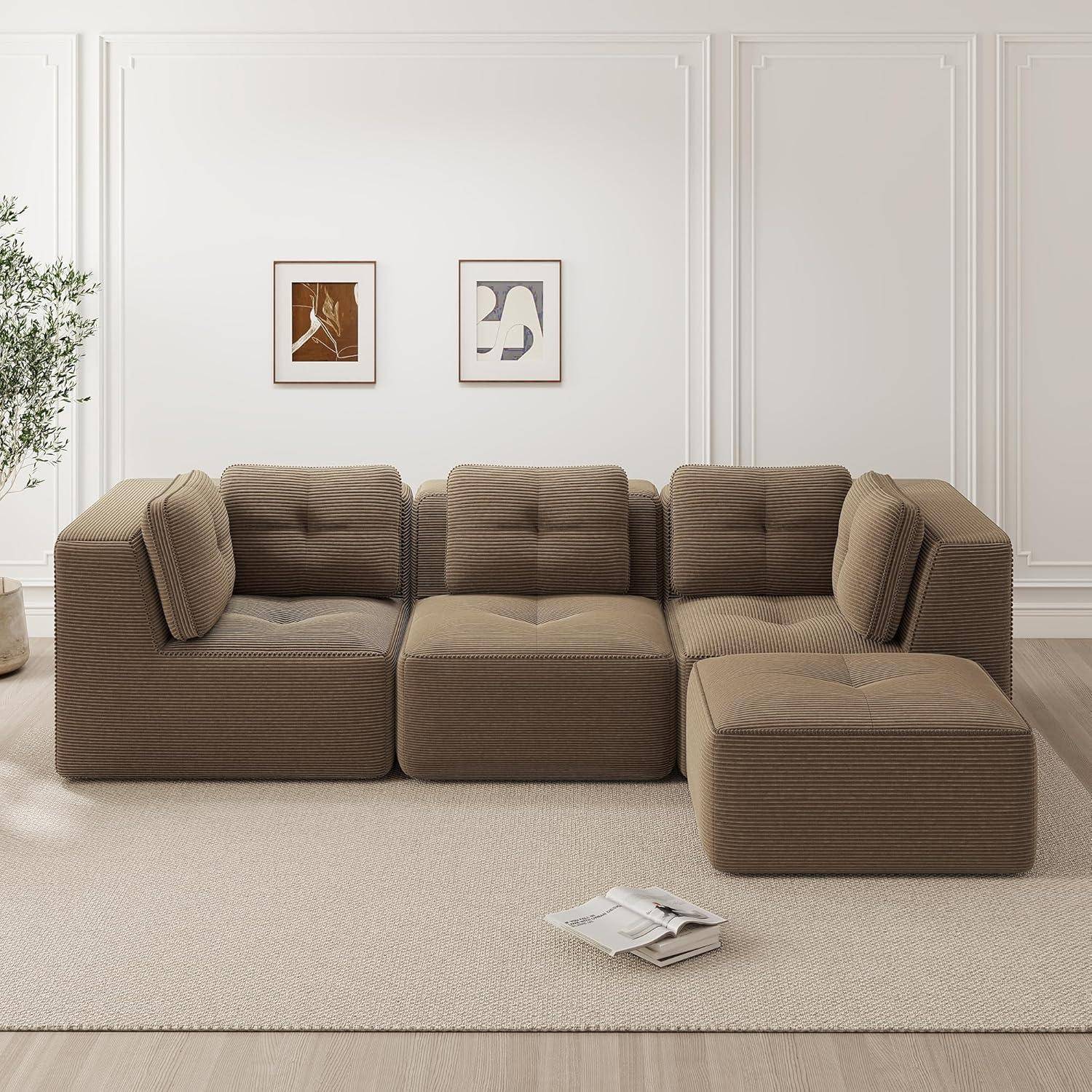 Modernes modulares braunes Sofa mit Kissen und Chaiselongue in einem minimalistischen Wohnzimmer, mit zwei gerahmten abstrakten Drucken an einer weißen Wand.