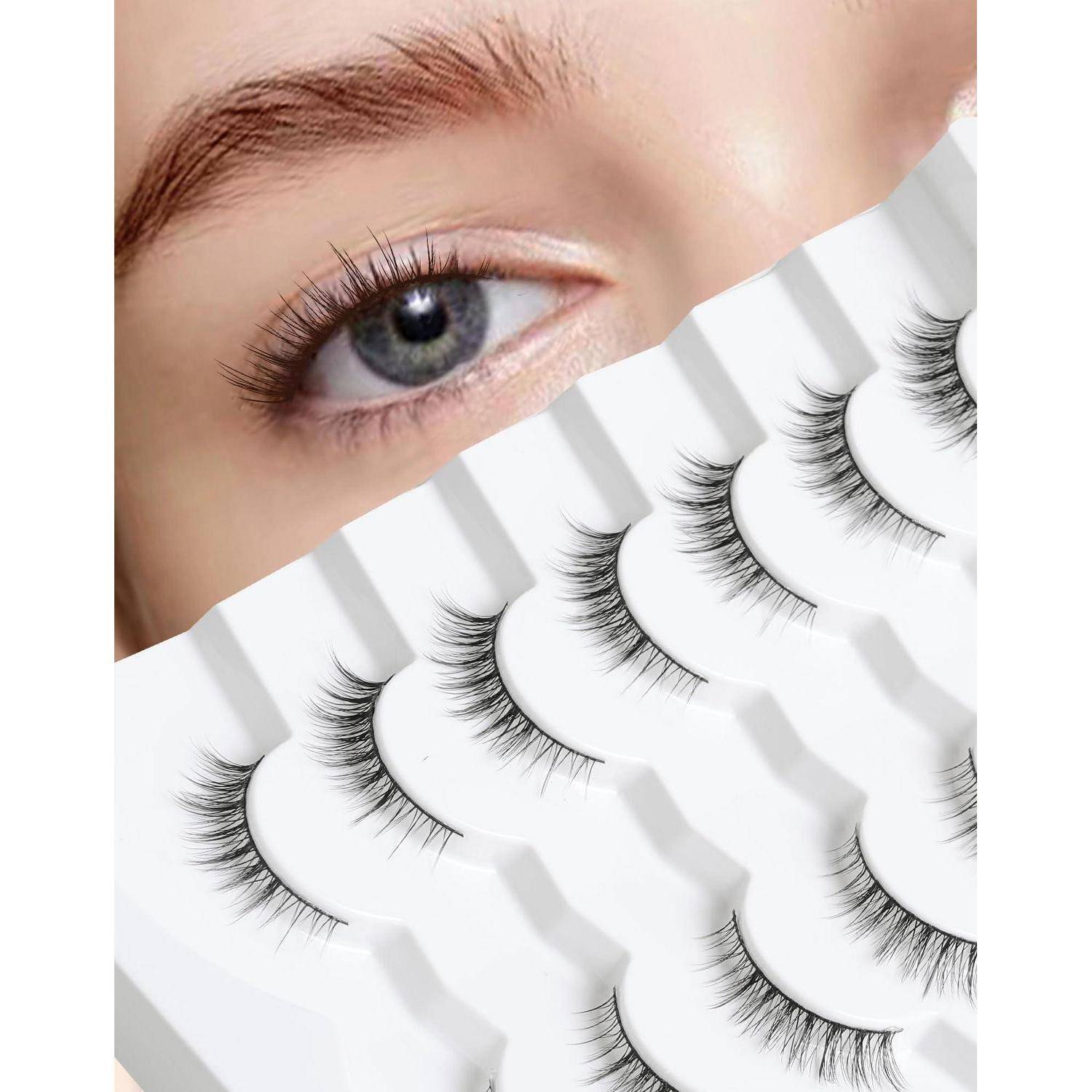 Nahaufnahme eines blauen Auges über einer Auslage mehrerer Paar falscher Wimpern, die in weißen Tabletts angeordnet sind.