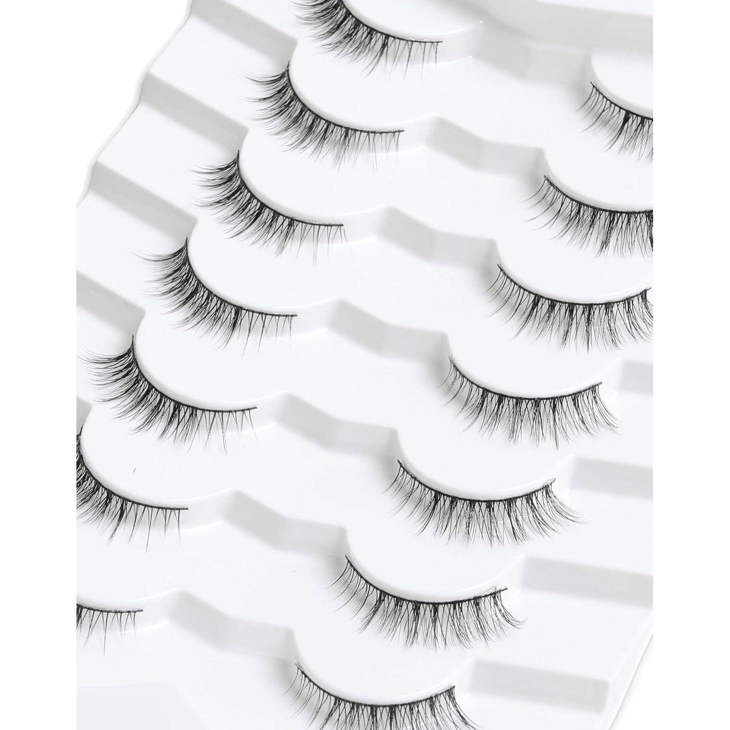 Mehrere falsche Wimpern in gestaffelten weißen Tabletts auf hellem Hintergrund angeordnet.