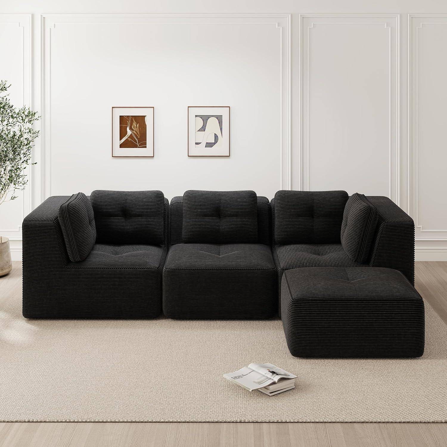 Schwarzes modulares Ecksofa mit Recamiere in einem minimalistischen Wohnzimmer, vor einer weiß getäfelten Wand mit zwei gerahmten Drucken.