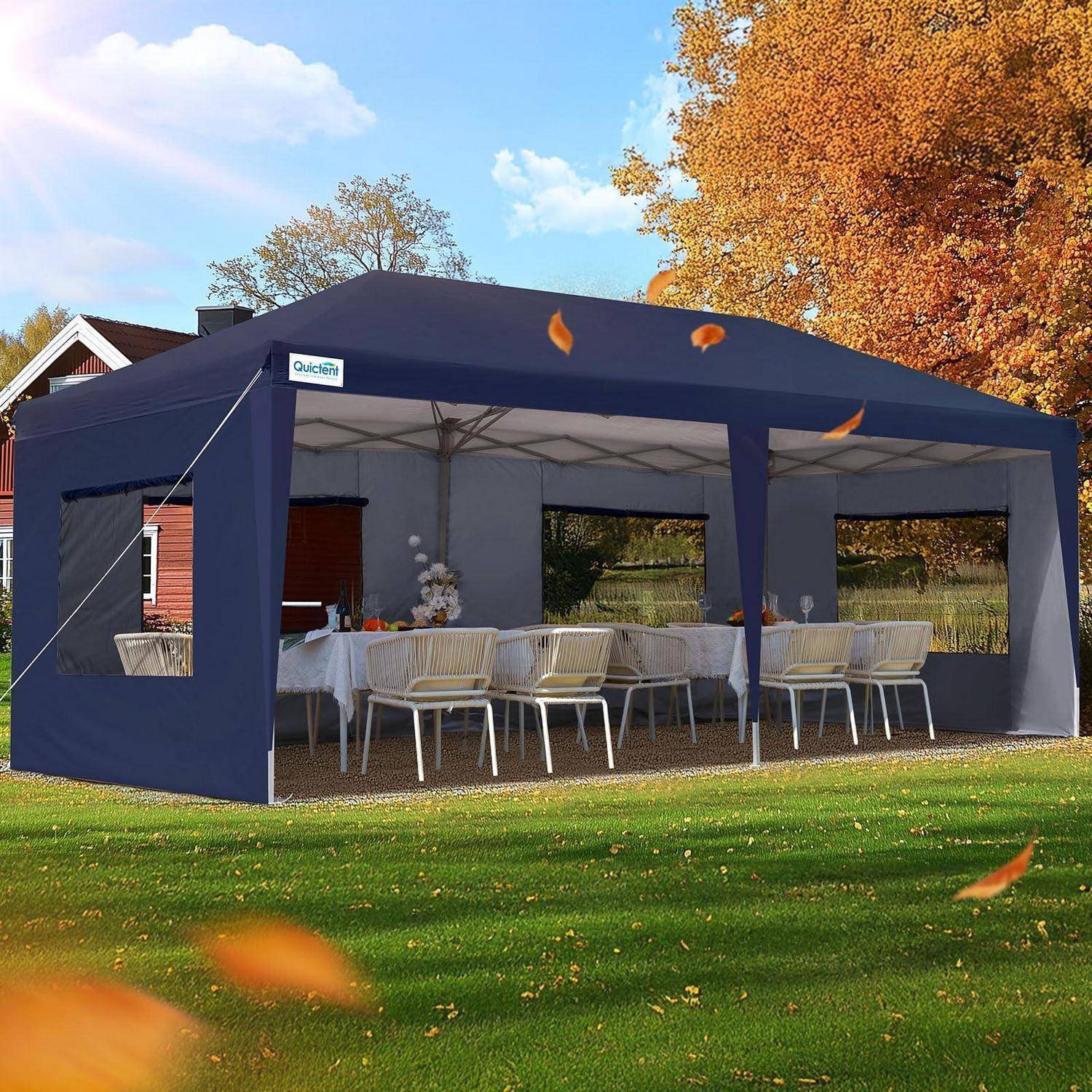 Ein marineblauer Außenzeltdach mit offenen Seiten schützt einen Tisch und Stühle auf einem Rasen, mit Herbstbäumen im Hintergrund.