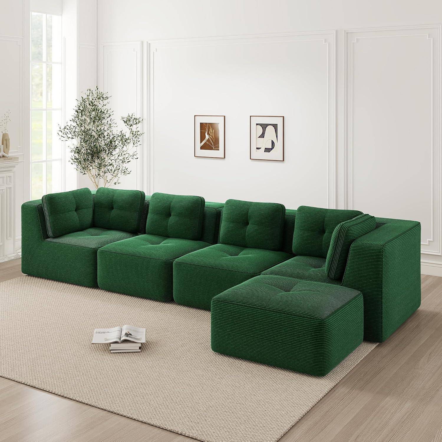 Grünes modulares Sectional-Sofa mit Chaiselongue in einem hellen minimalistische Wohnzimmer, mit gerahmten Wandbildern, einer Pflanze und einem offenen Buch auf dem Teppich.