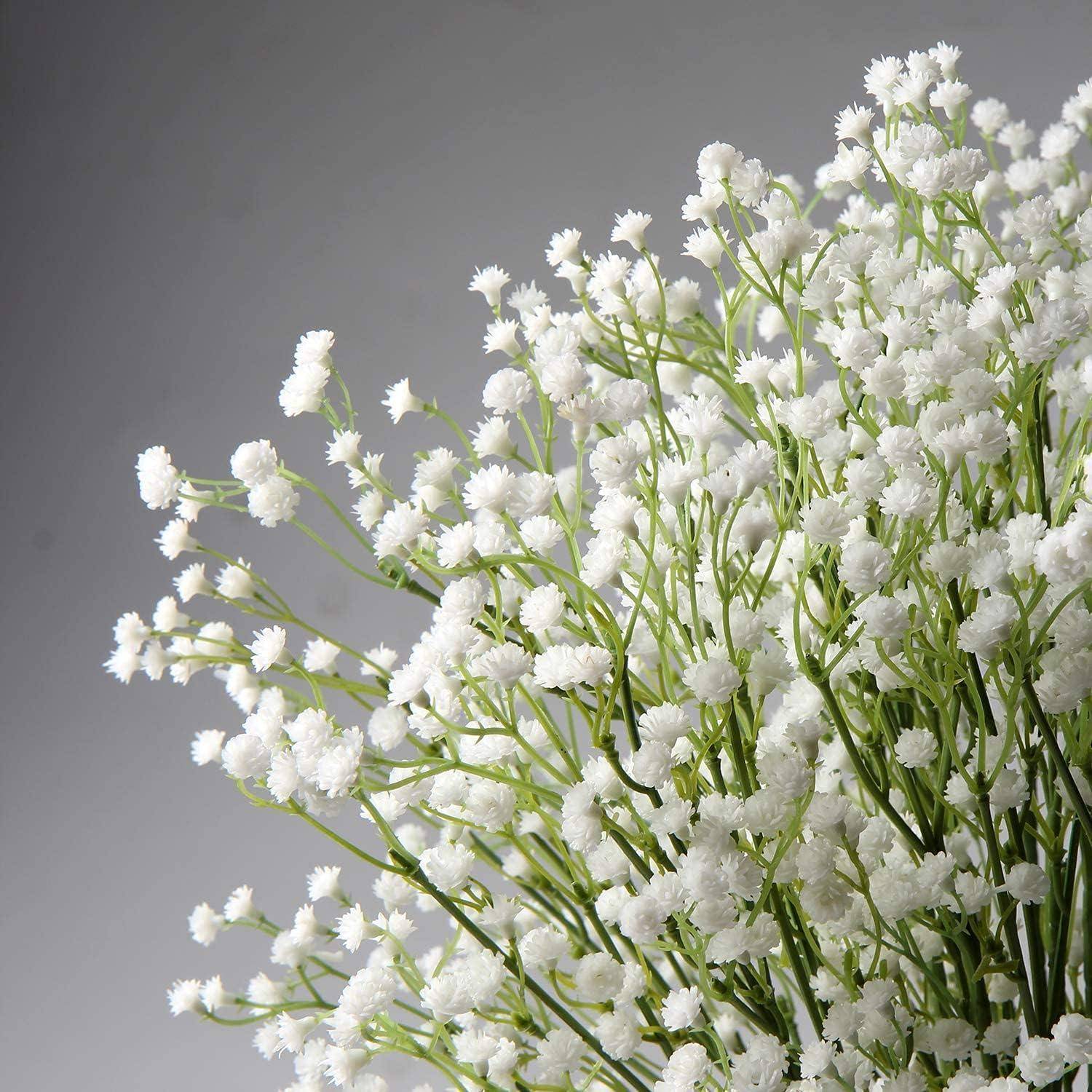 Nahaufnahme eines Straußes aus kleinen weißen Blüten mit grünen Stielen vor einem schlichten grauem Hintergrund.