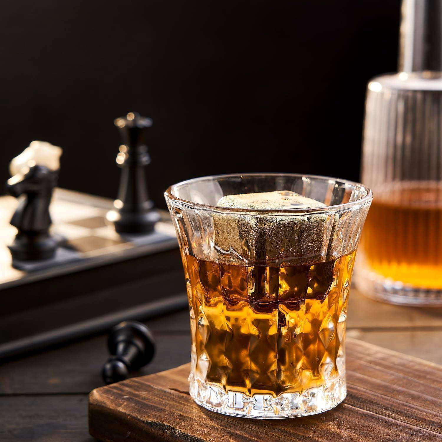 Ein Glas mit bernsteinfarbenem Eiskaltgetränk mit einer Zitronenscheibe und einem Schachbrett im Hintergrund auf einem Holztisch.