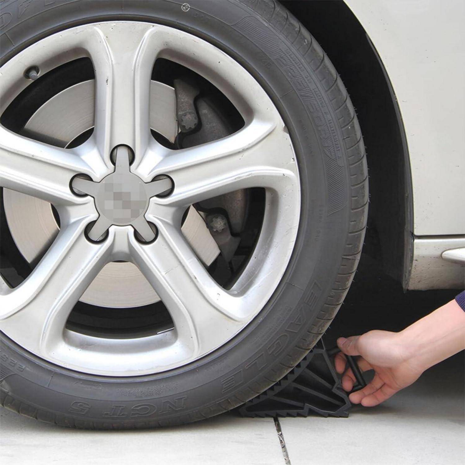 Hand, die einen Radkeil unter einen Autoreifen legt, um zu verhindern, dass das Fahrzeug wegrolt.