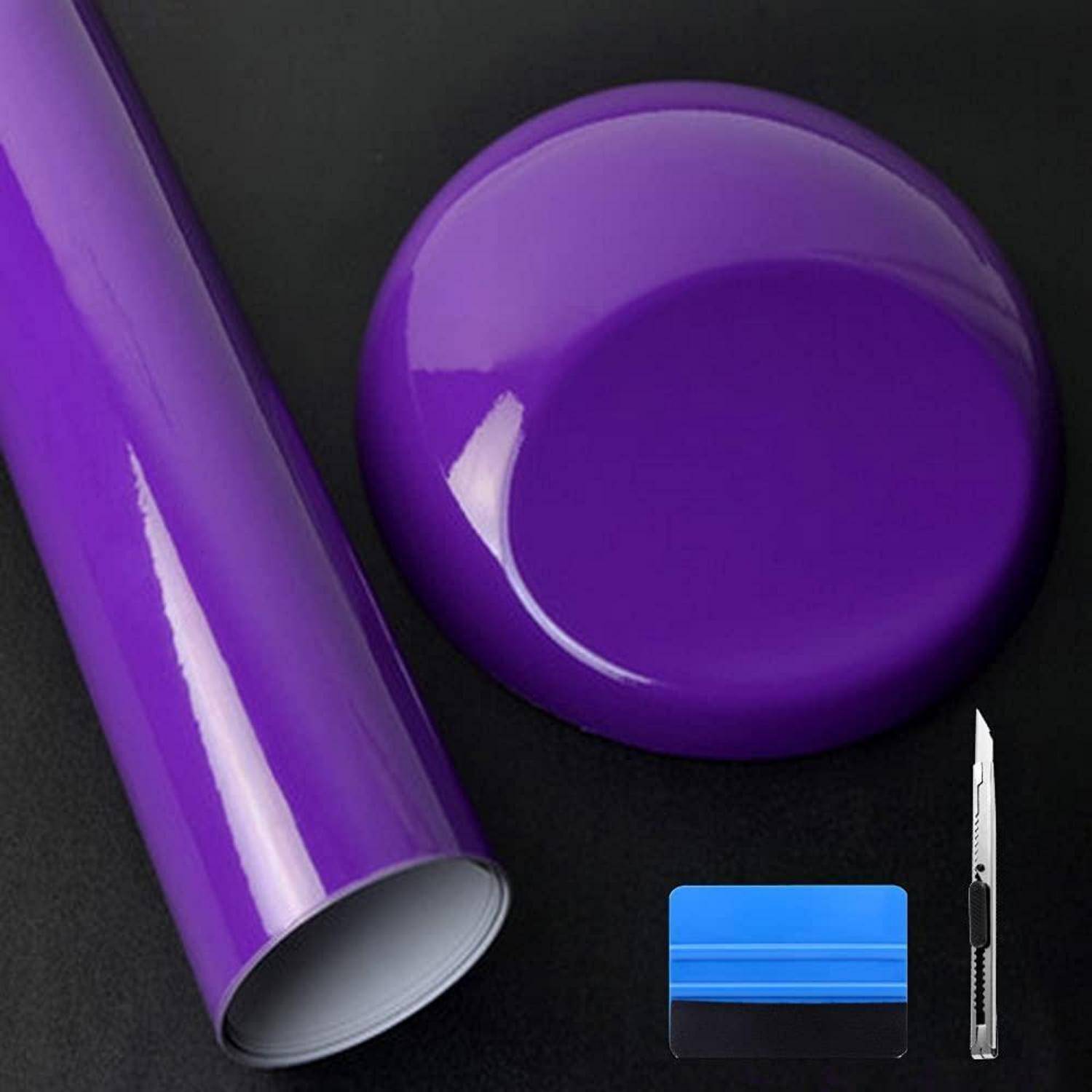 Rolle mit violettem Vinyl-Wrappingfilm und Rakelmes auf dunklem Hintergrund, zeigt Werkzeuge zum Anbringen oder Schneiden von Haftfolie.