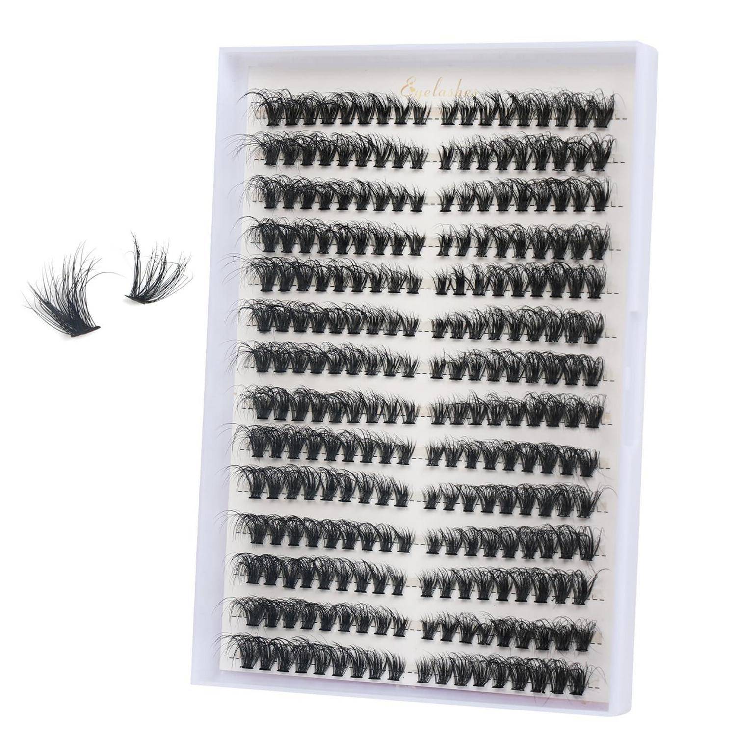 Tablett mit künstlichen Wimpern in Reihen, mit zwei lockeren Wimpernbündeln daneben auf weißem Hintergrund.