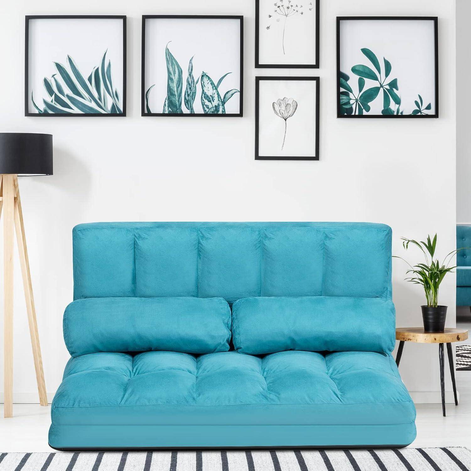 Türkises gestepptes Sofa in einem hellen Wohnzimmer, mit botanischer Wandkunst darüber, einer Stehlampe auf der linken Seite und einem kleinen Beistelltisch mit einer Pflanze auf der rechten Seite.