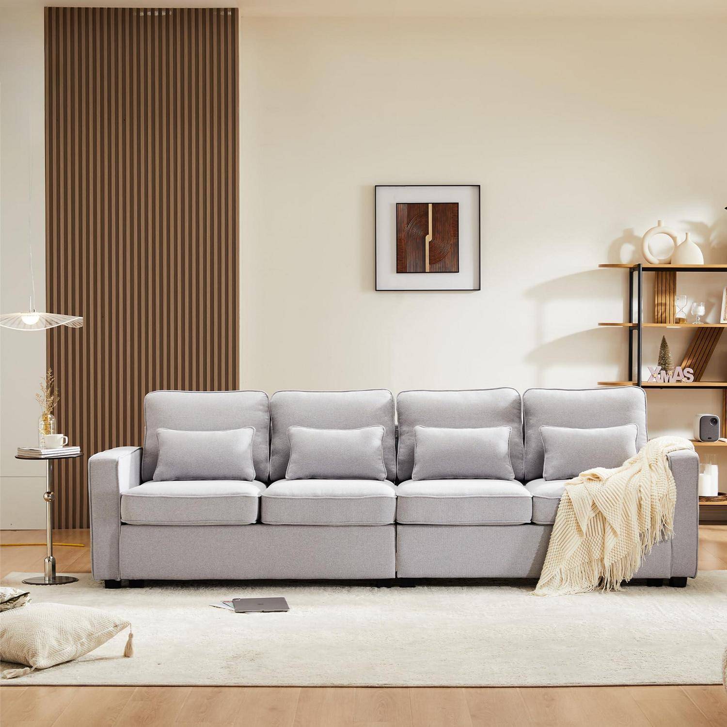 Ein hellgraues Sofa mit Kissen und einer Decke steht in einem minimalistischen Wohnzimmer mit einem Wanddruck im Rahmen, einer Holzlattenverzierung und seitlichen Regalen.