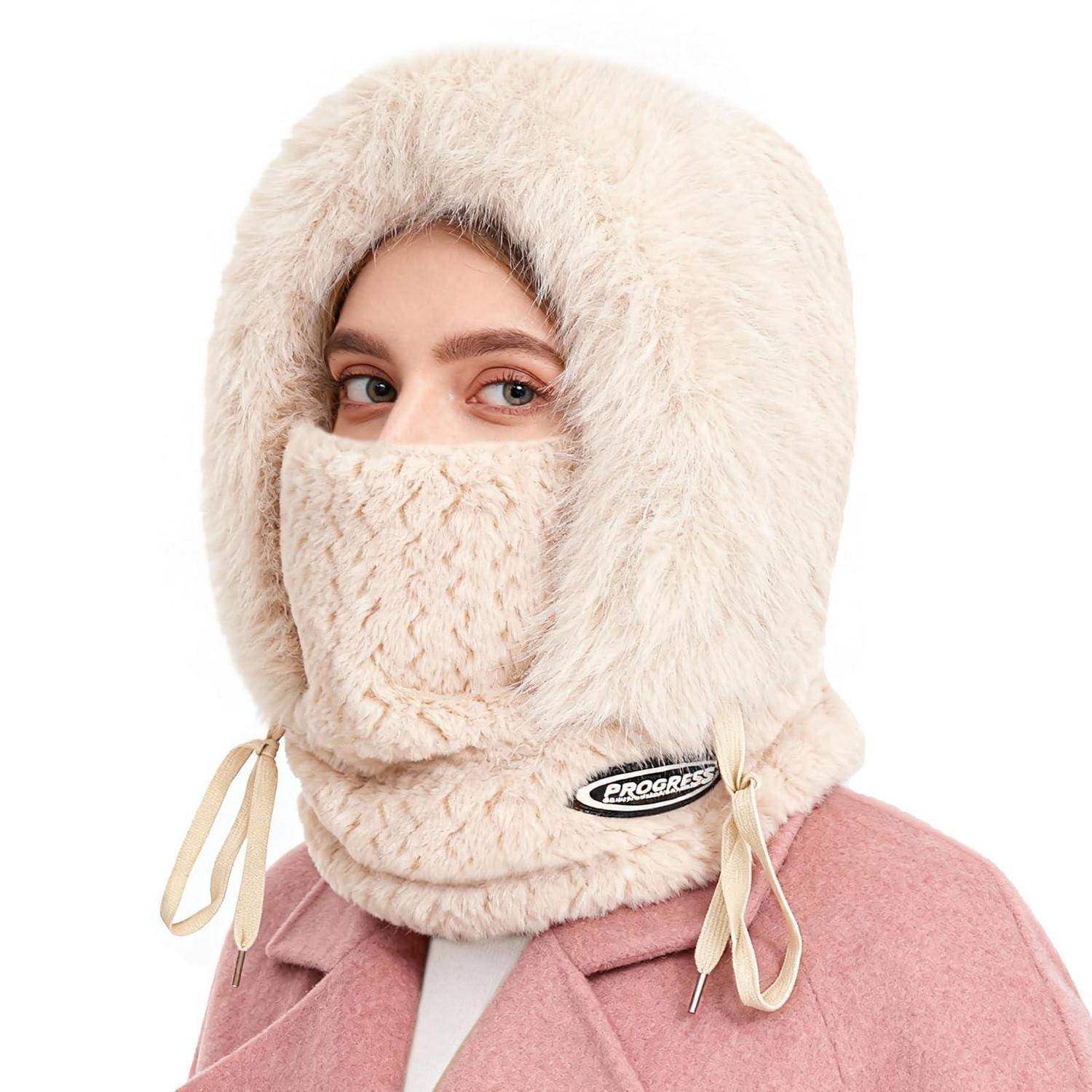 Person mit einer cremefarbenen, pelzgefütterten Winterkapuze und Gesichtsverhüllung, wobei nur die Augen sichtbar sind, über einem rosa Mantel.