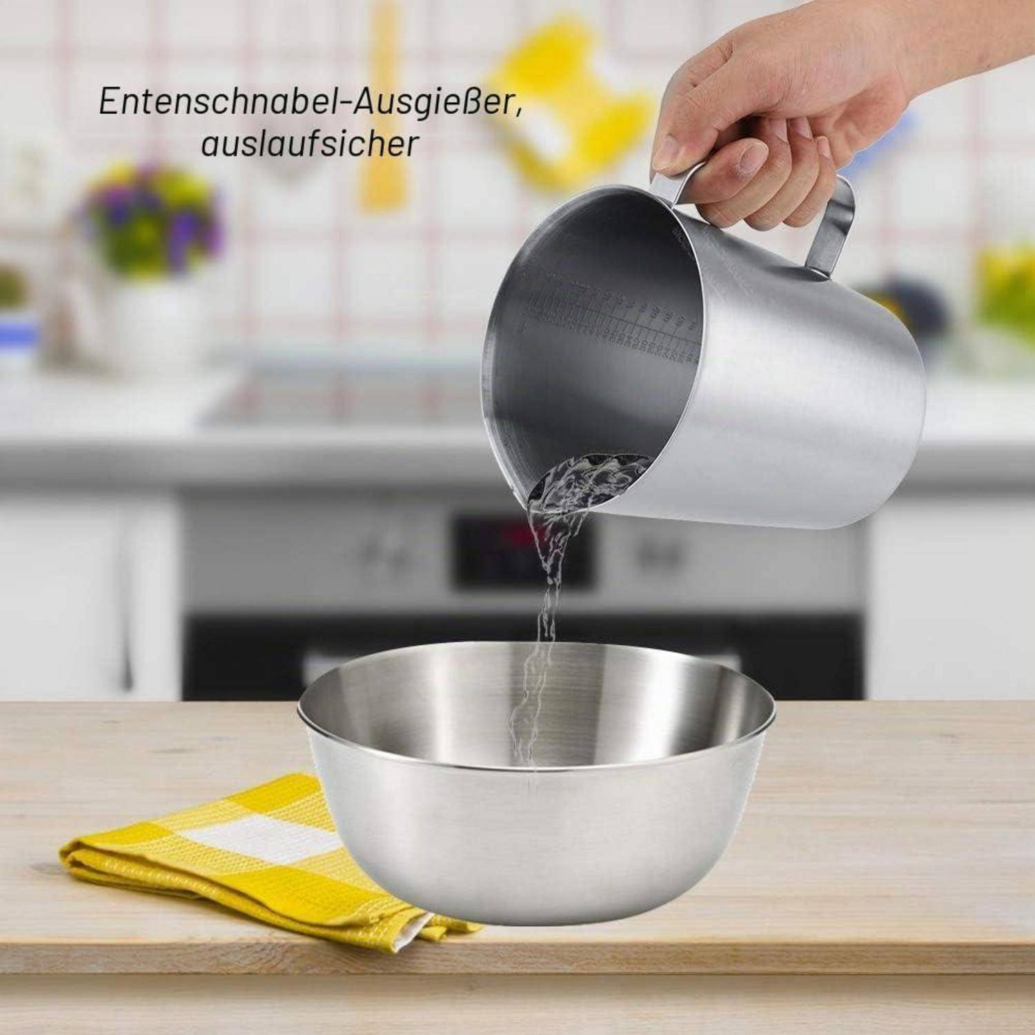 Eine Hand gießt Wasser aus einem Edelstahlkrug in eine Edelstahlmischschüssel auf einer Küchenarbeitsplatte; deutscher Text besagt „schnabelartiger Ausguss, tropfenfreies Gießen".