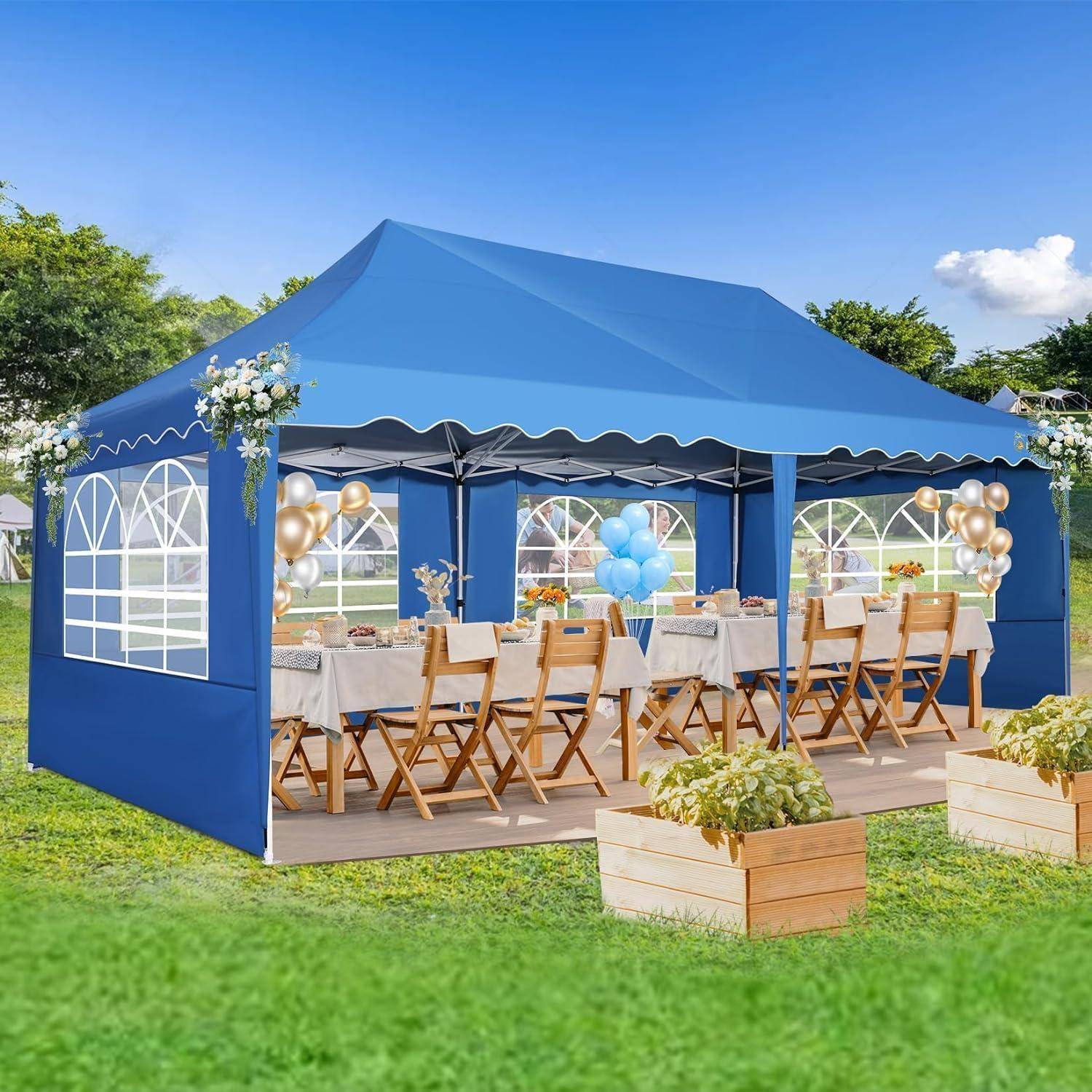 Blaues Außenveranstaltungszelt mit offenen Seiten, Tische und Holzstühle für eine Party eingerichtet, dekoriert mit Ballons und Blumen auf einem Rasen.