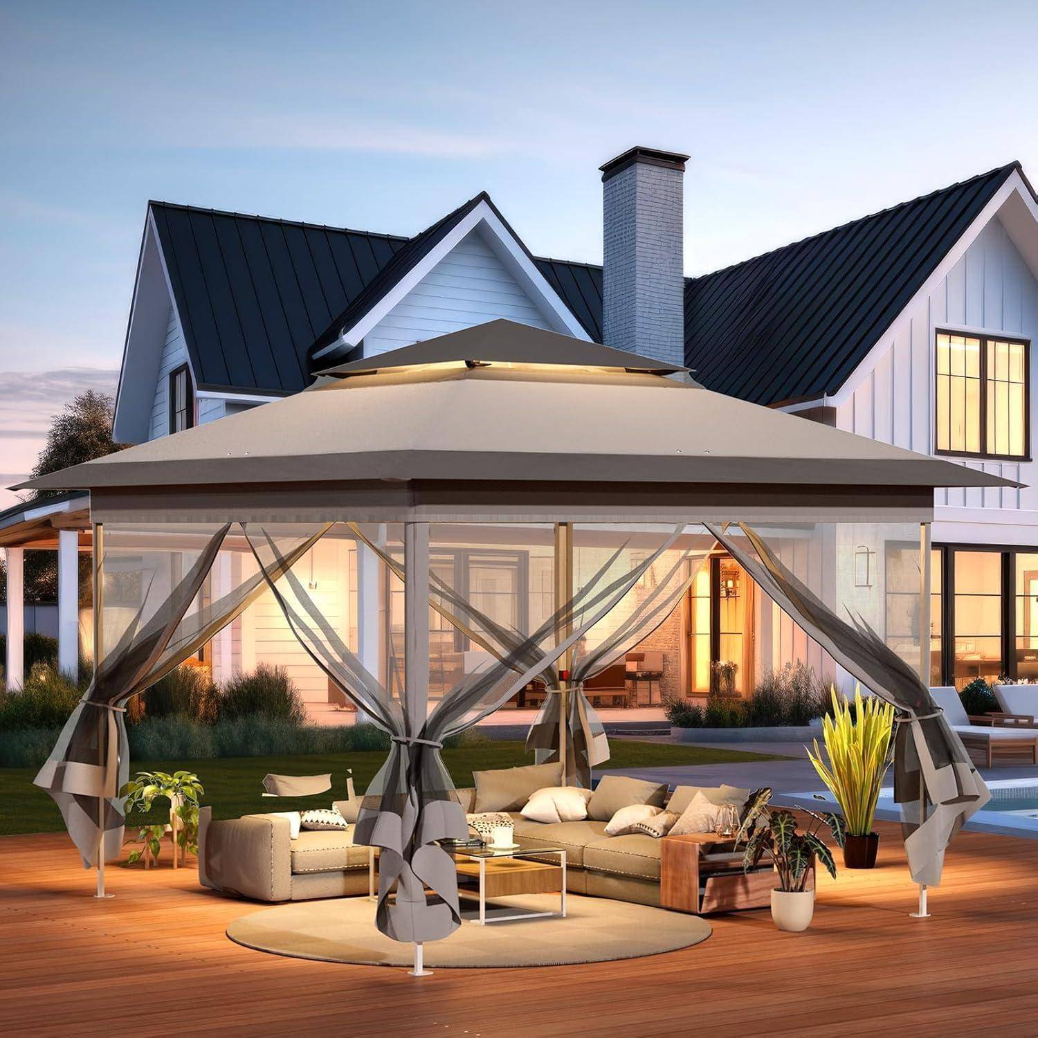 Hinterhof-Terrasse mit einem großen beigefarbenen Gazebo-Baldachin über einem Außensitzbereich vor einem modernen Haus in der Dämmerung.