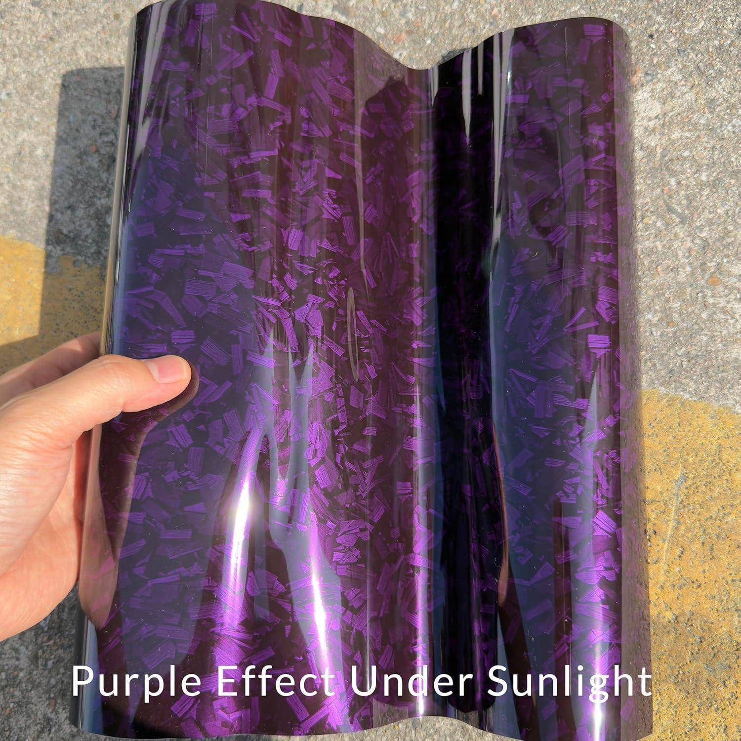 Eine Hand, die einen glänzenden violetten reflektierenden Film im Freien in der Sonne hält, wobei eine schimmernde gemusterte Oberfläche sichtbar ist.