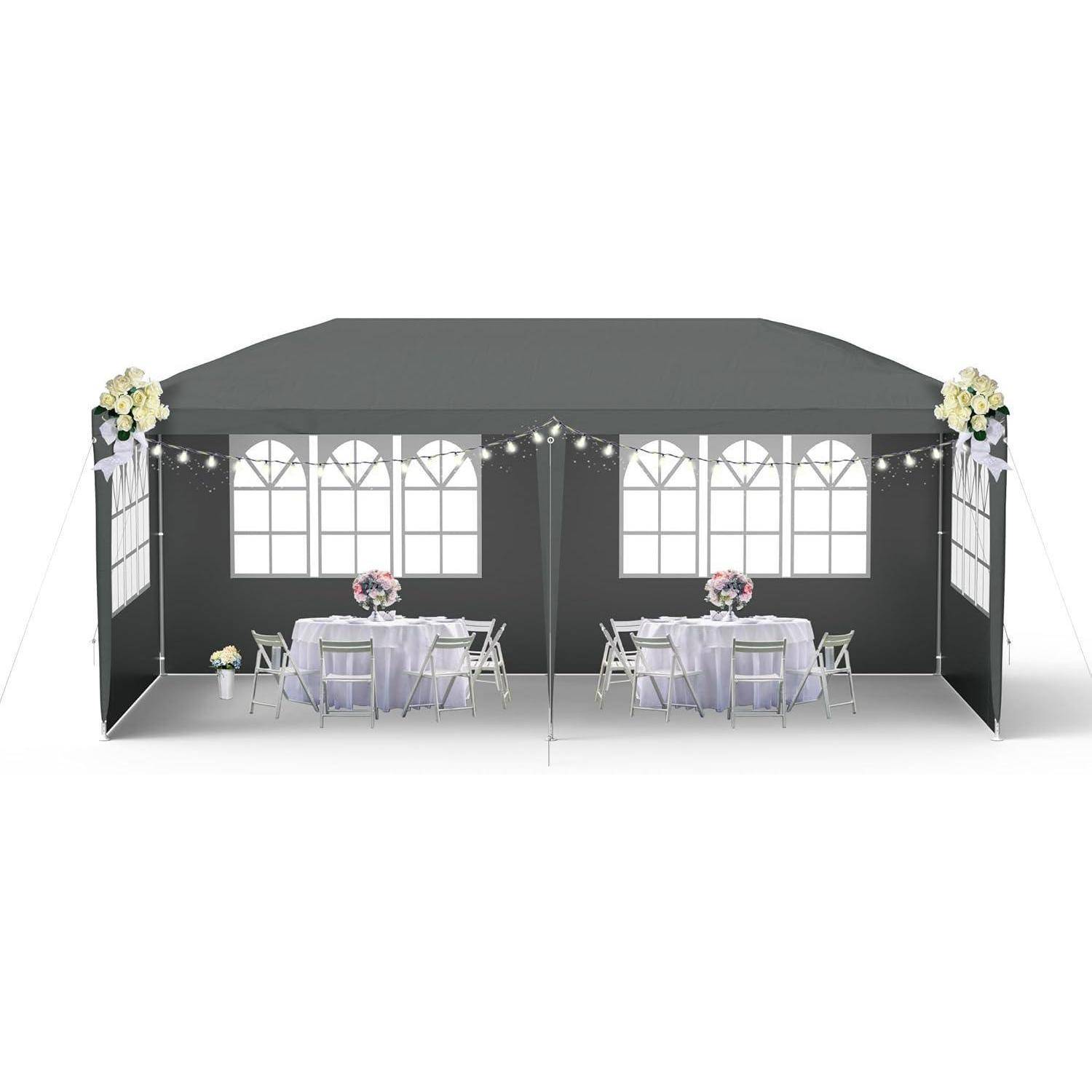 Ein dekoriertes schwarzes Eventszelt mit gewölbten Fensterteilen, Lichterketten und zwei kleine runde Tische mit Stühlen und floralen Mittelpunktsdekorationen.