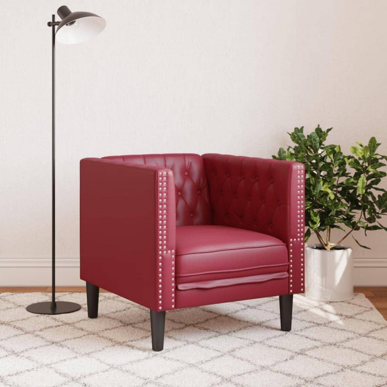 Roter gepolsterter Sessel mit gesteppten Seitenflächen steht auf einem gemusterten Teppich neben einer Stehlampe und einer Topfpflanze in einem hellen Raum.