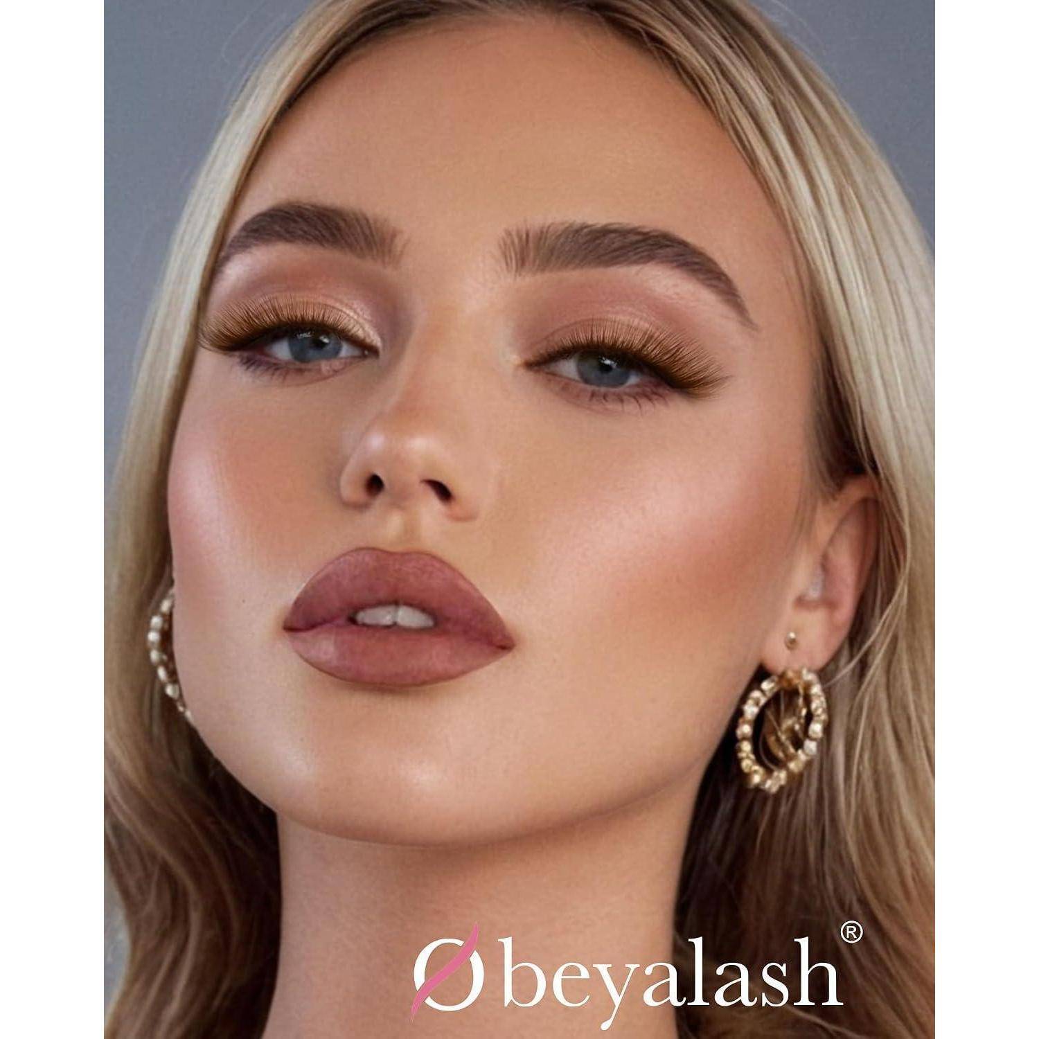 Nahaufnahmeportrait einer Frau mit dramatischem Make-up und goldenen Creolen; das Logo 