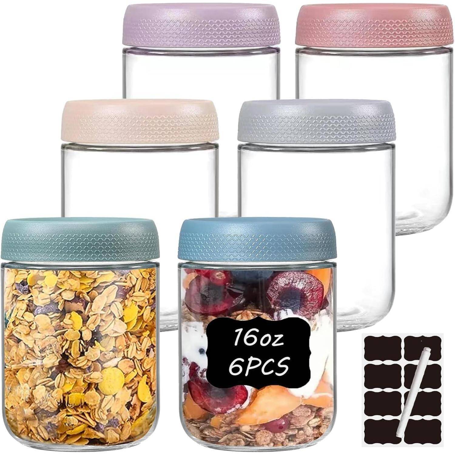 Sechs Glasspeicherbehälter mit Pastelldeckeln, zwei davon mit Lebensmitteln gefüllt, plus Etikettaufkleber und ein Markierungsstift.