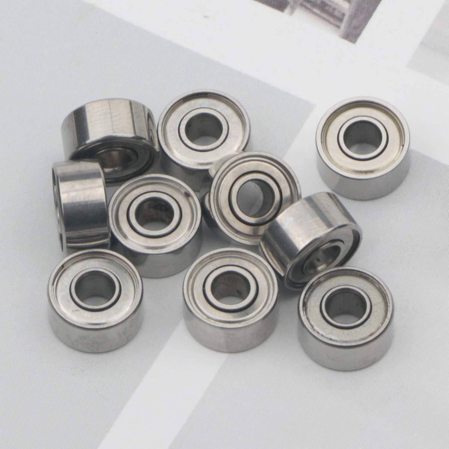 Neun kleine Metallkugellager auf einer leichten Oberfläche angeordnet, eine Nahaufnahme von glänzenden kreisförmigen Maschinenteilen.