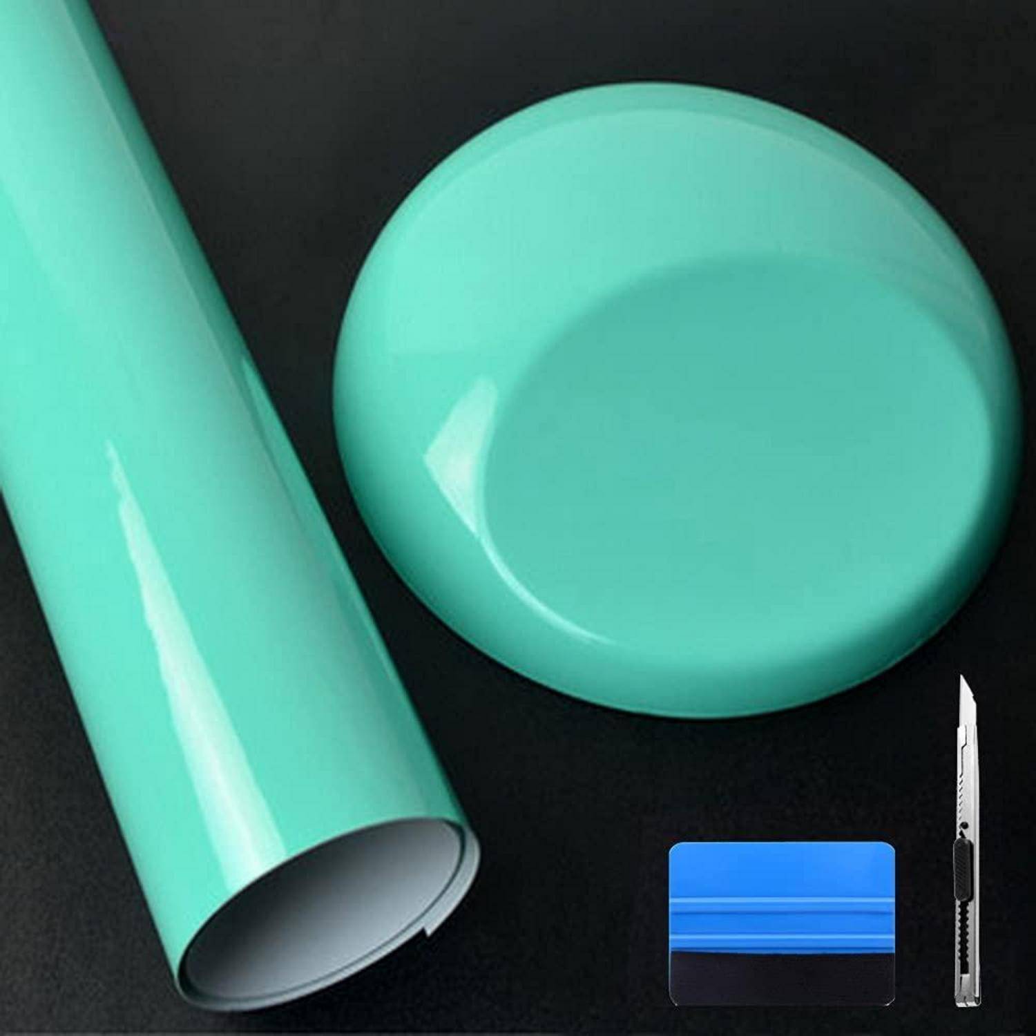 Türkisefarbene Klebebandrolle und rundes Blatt mit blauem Rakel und Universalmesser auf schwarzem Hintergrund.