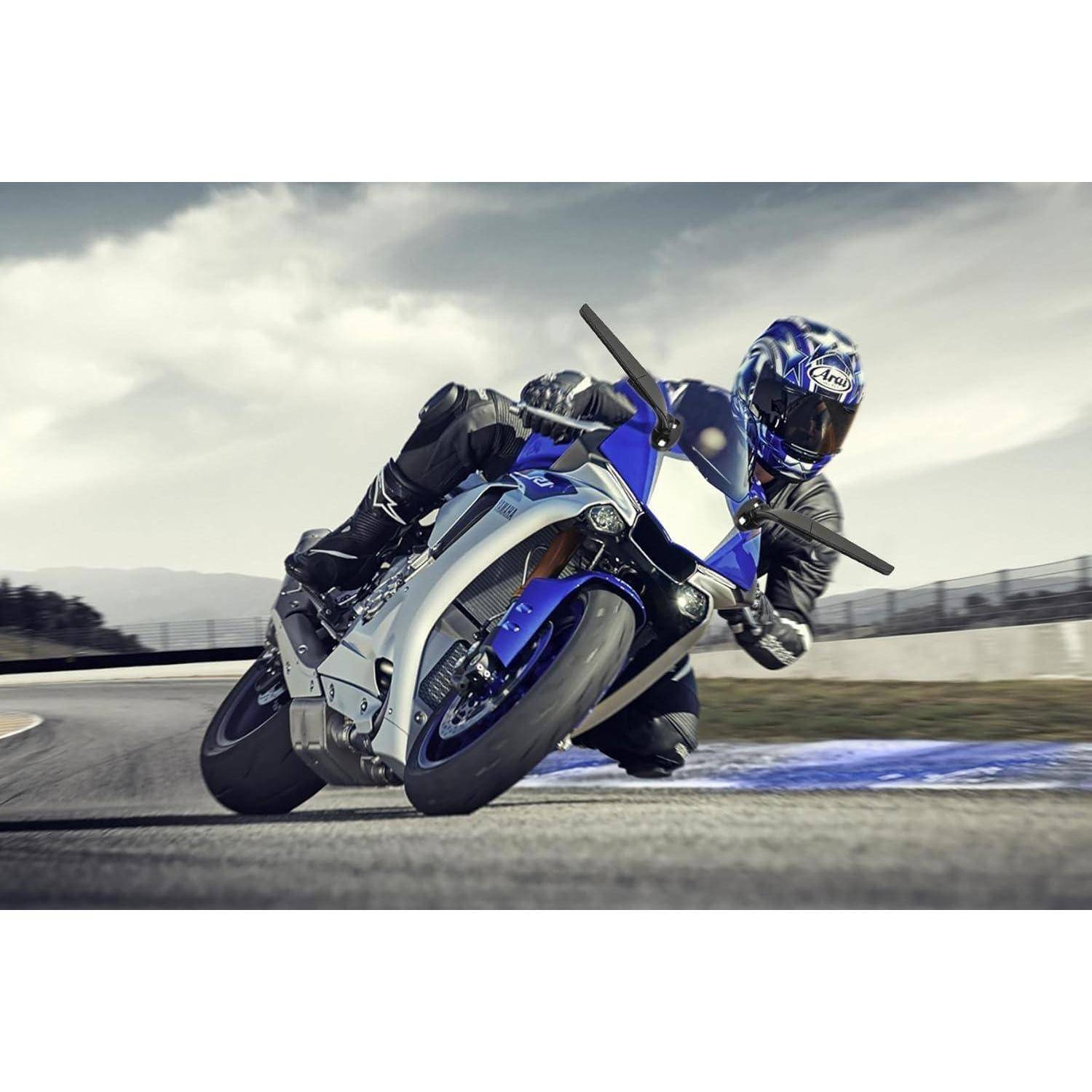 Ein Motorradfahrer lehnt sich scharf in eine Kurve auf einem blauen Sportmotorrad auf einer Rennstrecke, mit Bewegungsunschärfe und bewölktem Himmel im Hintergrund.