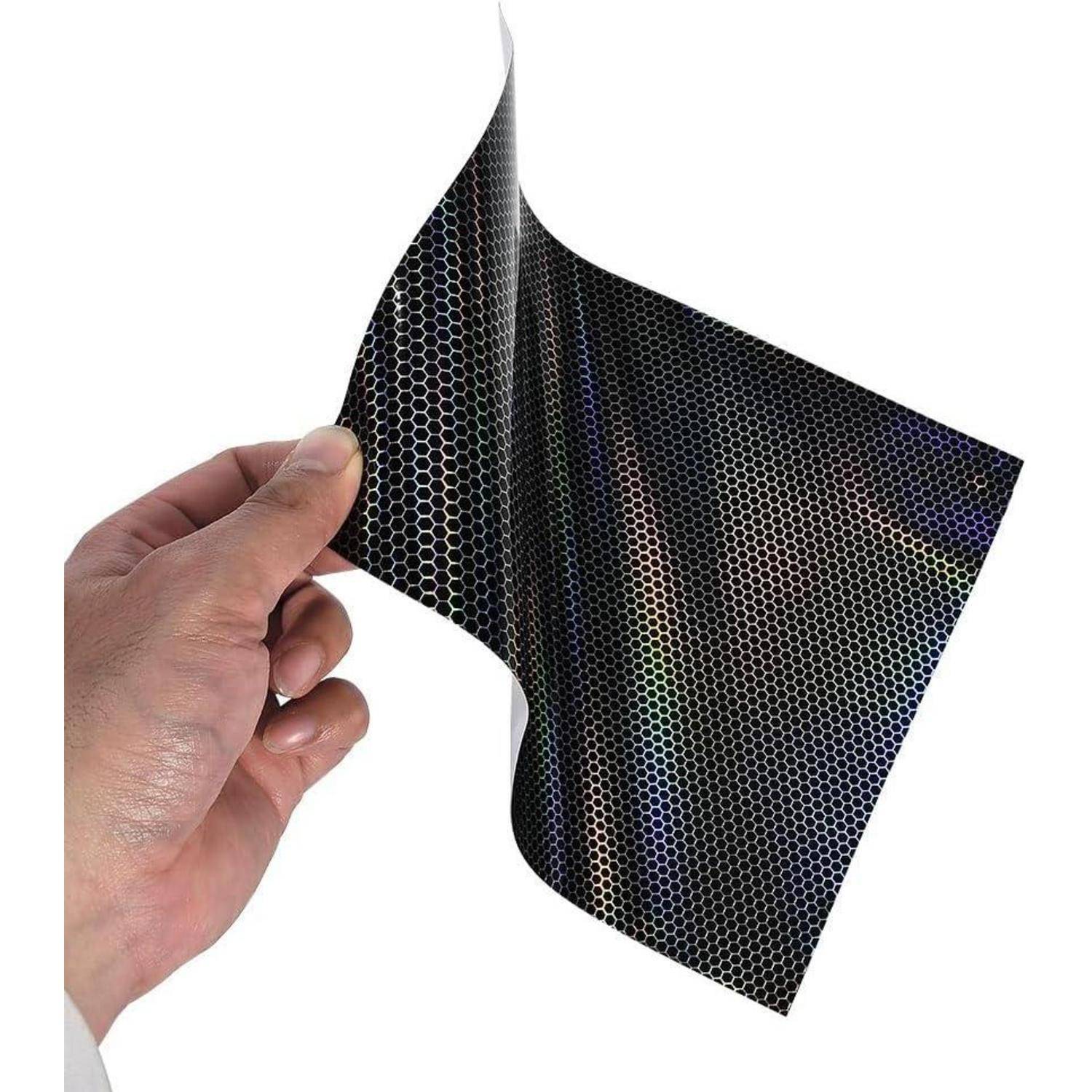 Hand hält ein flexibles, schwarzes Blatt mit Wabenstruktur-Muster gegen einen weißen Hintergrund.