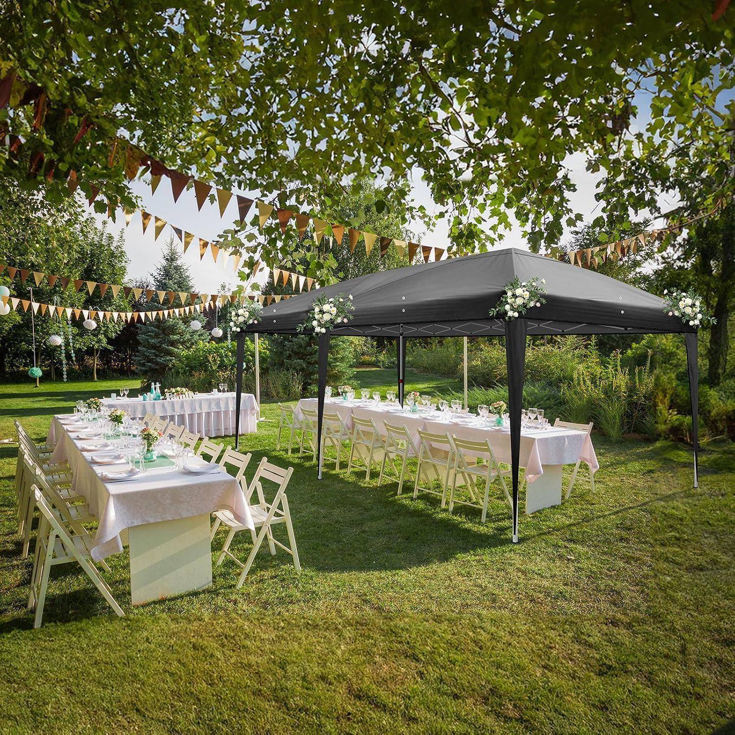 Outdoor-Gartenparty-Setup mit langen weißen Tischen und Klapstühlen unter einem schwarzen Baldachin, dekoriert mit Wimpelketten und Blumenelementen.