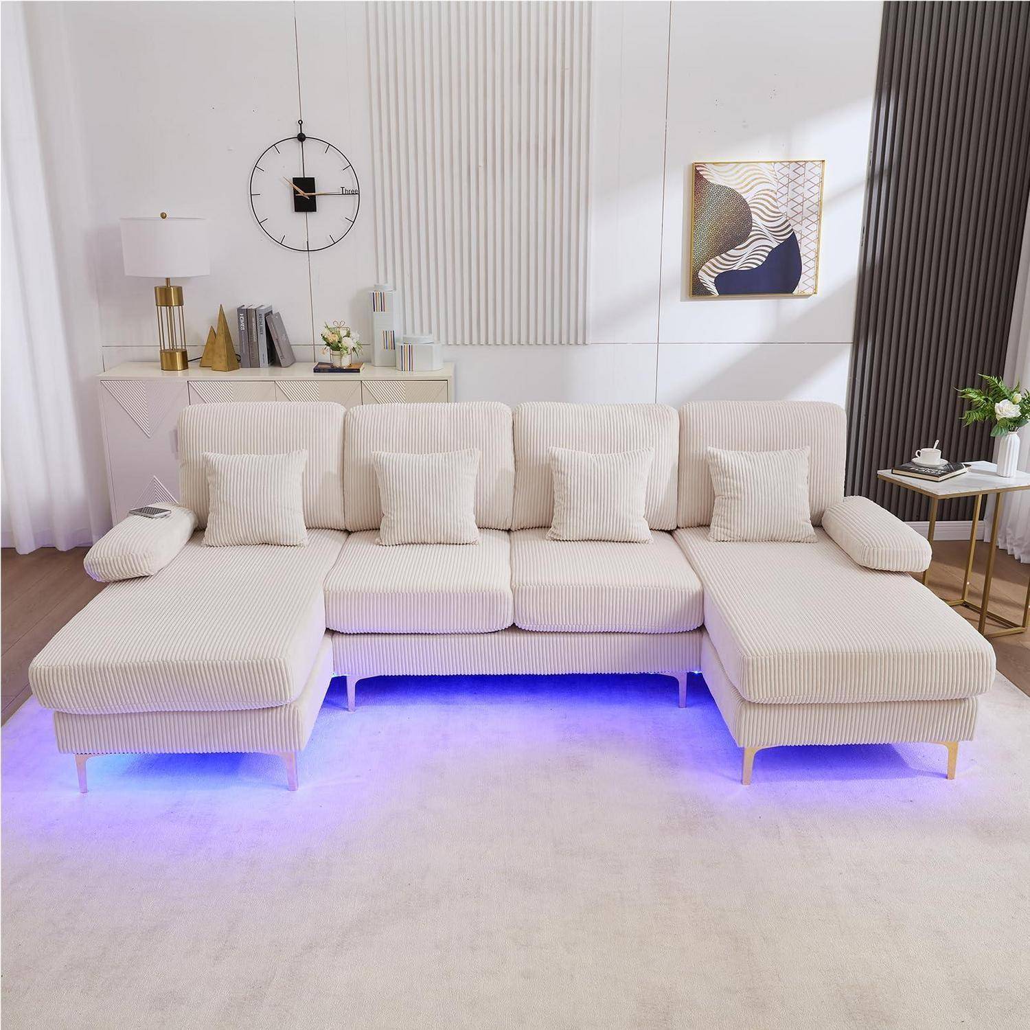 Modernes beiges Ecksofa mit Kissen in einem hellen Wohnzimmer, beleuchtet durch blaue LED-Beleuchtung unter dem Sofa.