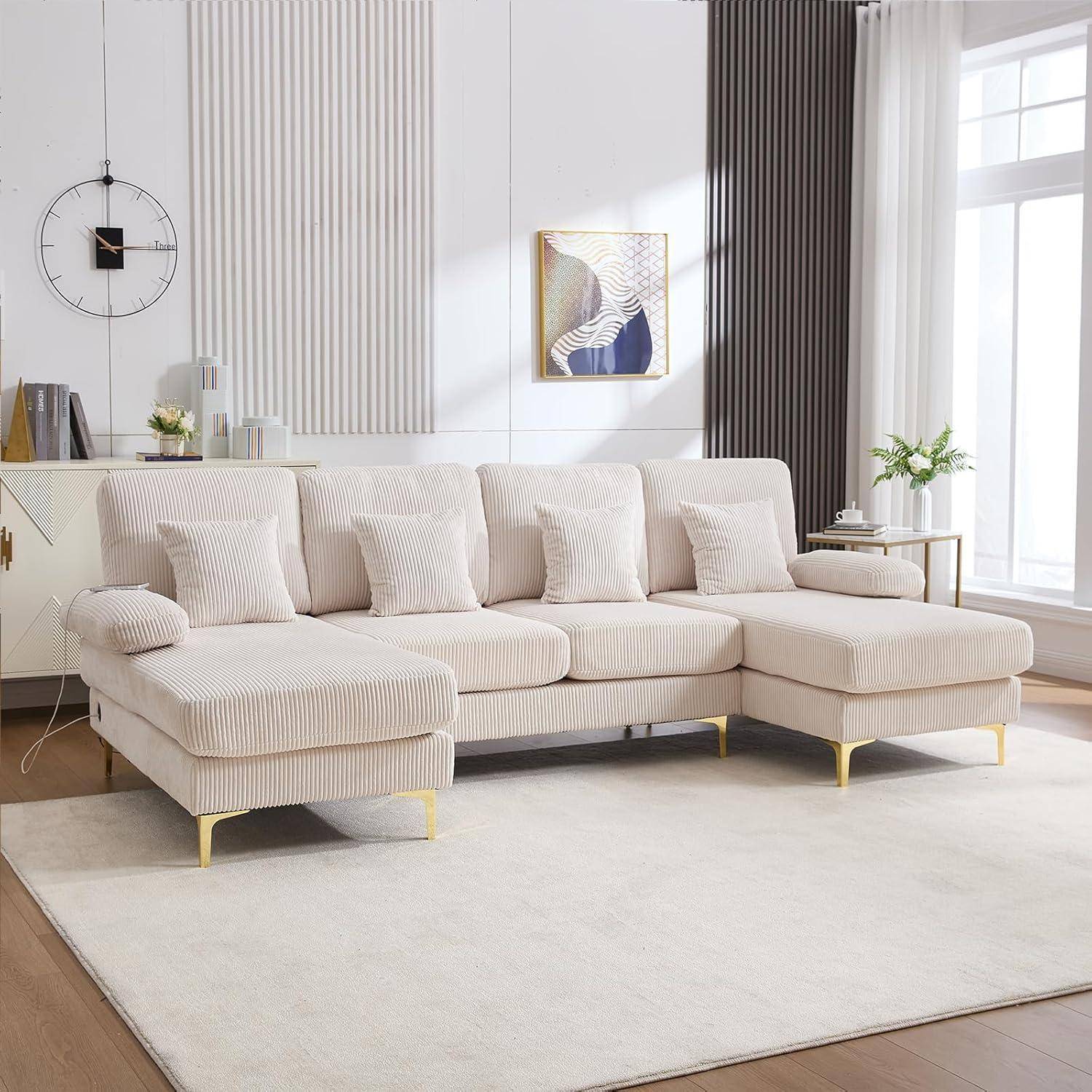 Hellbeiges Ecksofa mit Récamiere in einem hellen modernen Wohnzimmer, ausgestattet mit Kissen, Wandkunst, Uhr und großem Teppich.