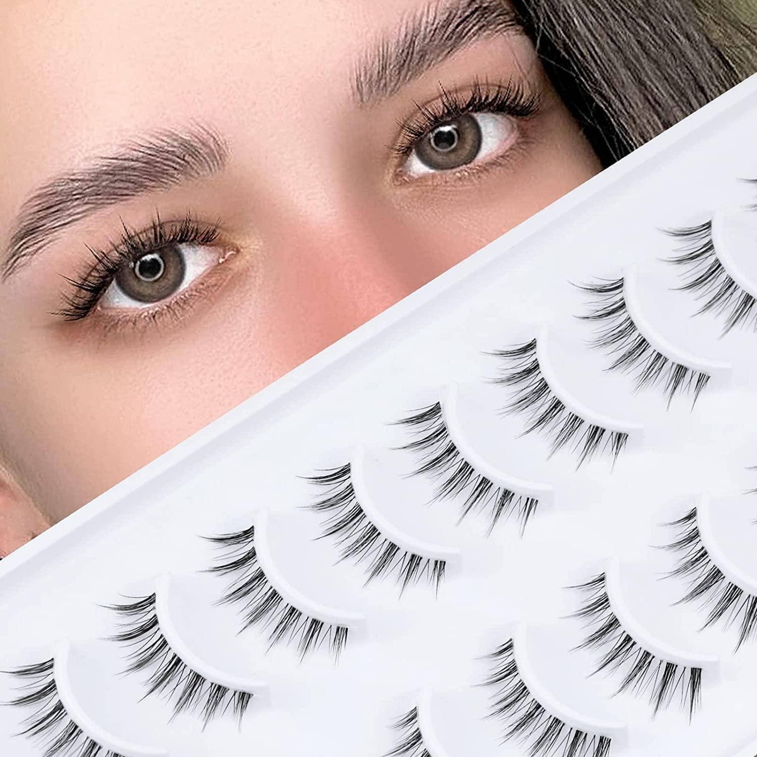 Nahaufnahme der Augen einer Frau über einer Anzeige von künstlichen Wimpernstreifen auf weißen Tabletts.