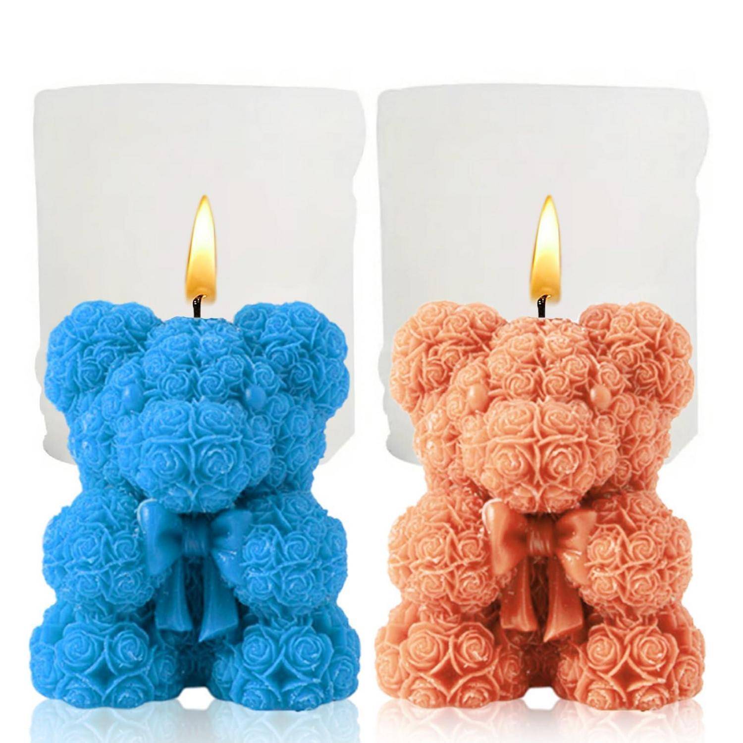 Zwei dekorative Teddybär-Kerzen, eine blau und eine pfirsichfarben, jeweils mit einer brennenden Docht.