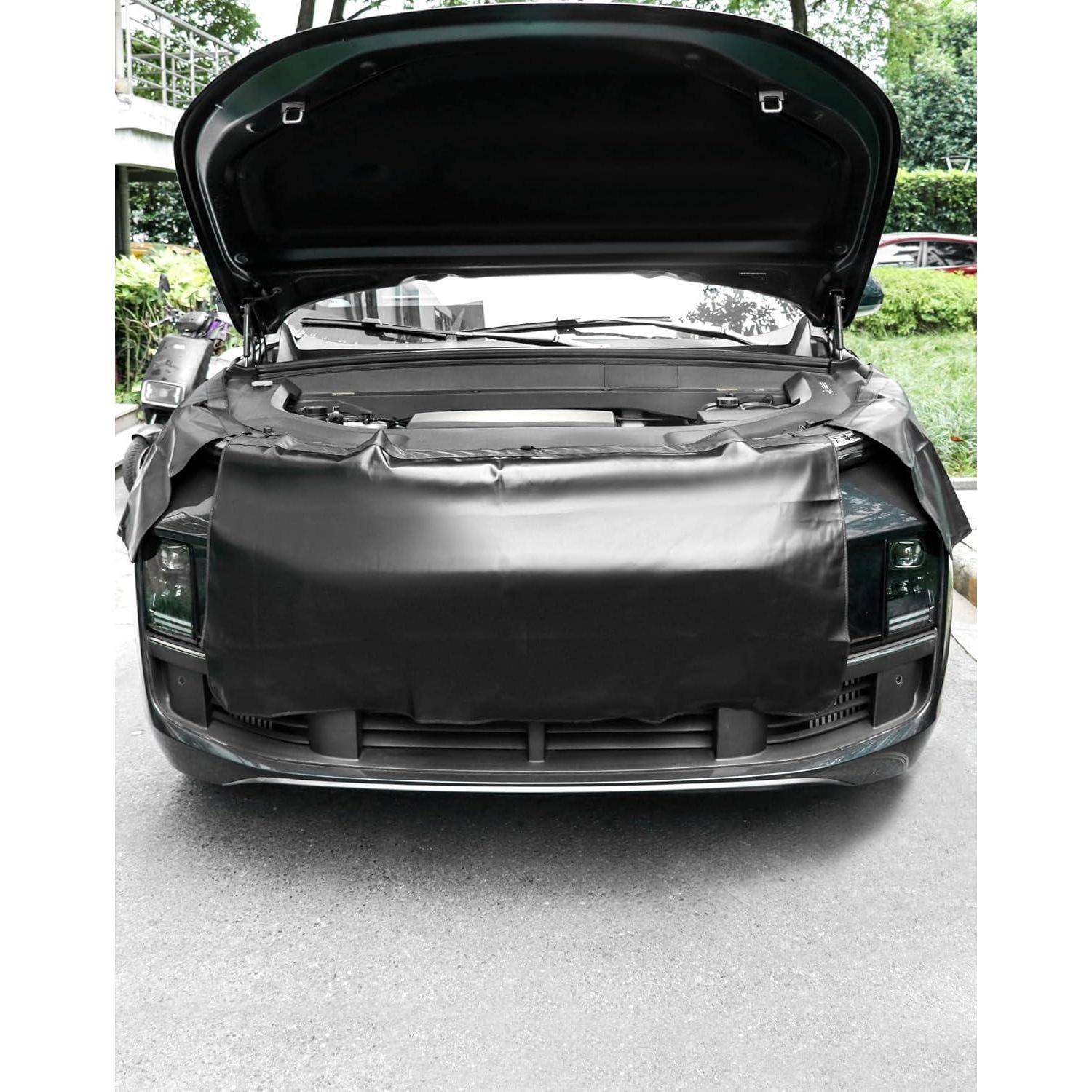 Vorderansicht eines schwarzen Autos mit offener Motorhaube, die umfangreiche Schäden im vorderen Bereich und einen abgedeckten Kühlergrill-/Stoßfängerbereich zeigt.