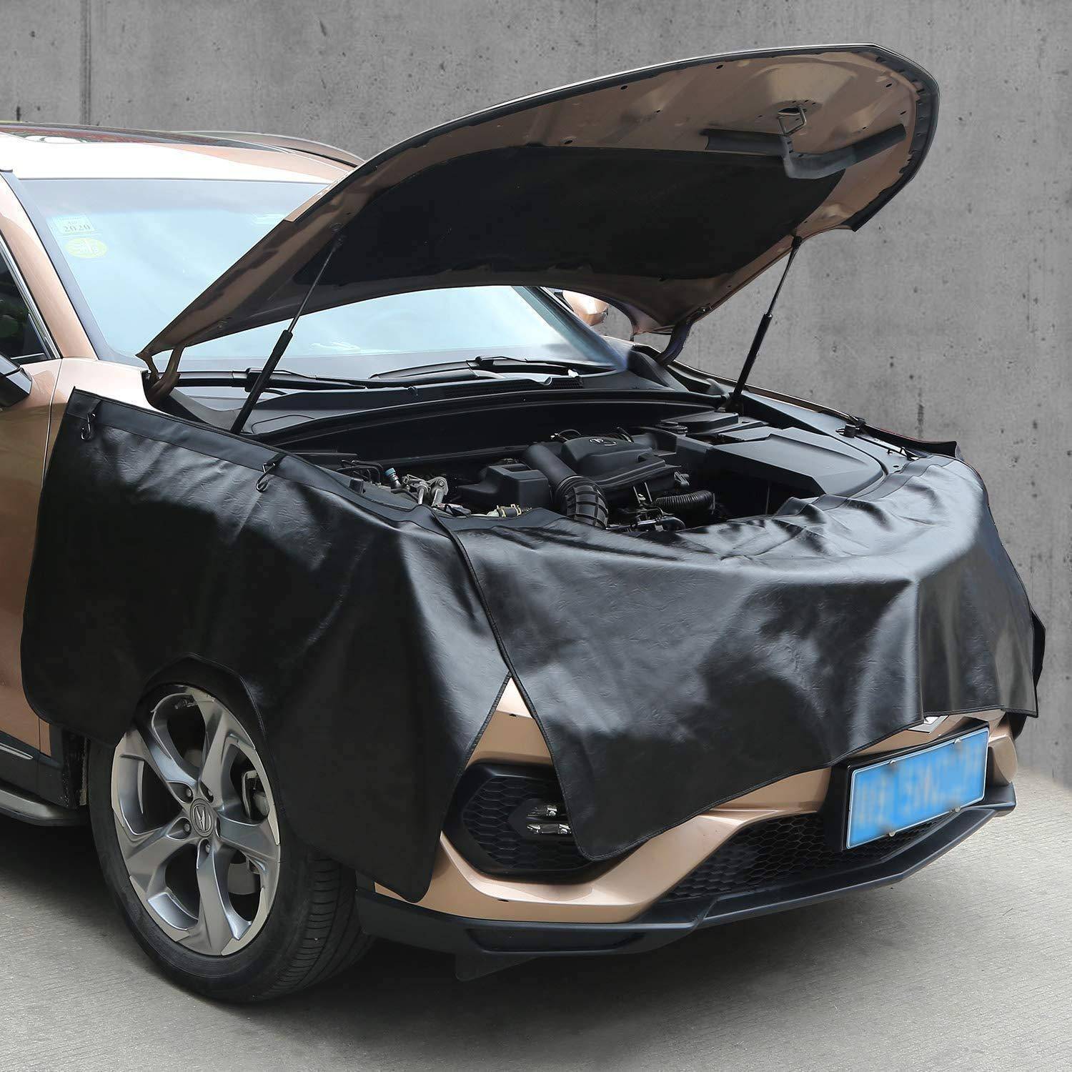 SUV mit offener Motorhaube, abgedeckt mit einer schwarzen Schutzfolie über der Front, während es gegen eine Betonwand geparkt ist.