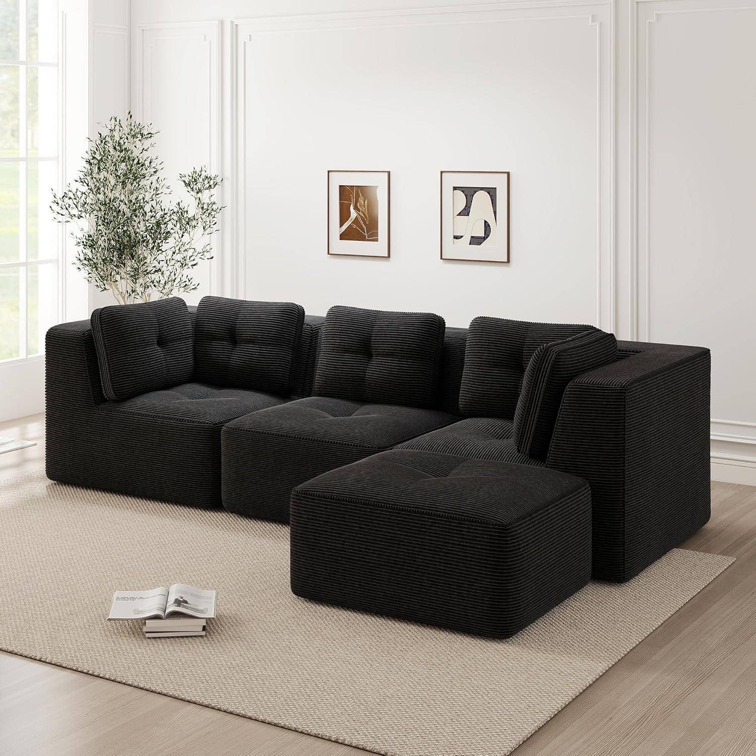 Schwarzes modulares Ecksofa mit Ottomane in einem hellen minimalistischen Wohnzimmer mit gerahmten Wandbildern, Pflanze und Teppich.