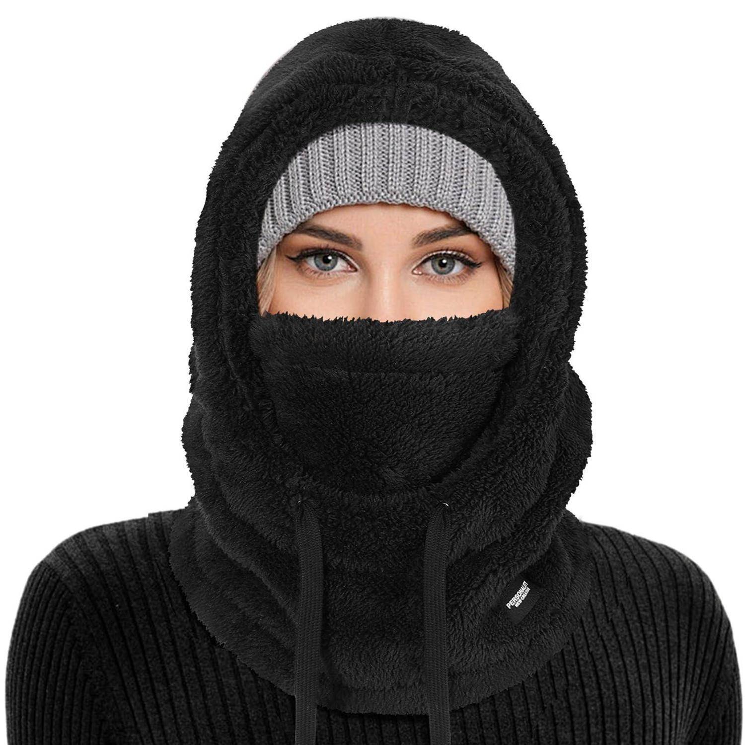 Person trägt eine schwarze Wintermütze (Balaclava) und eine graue Strickmütze, wobei nur die Augen auf weißem Hintergrund sichtbar sind.