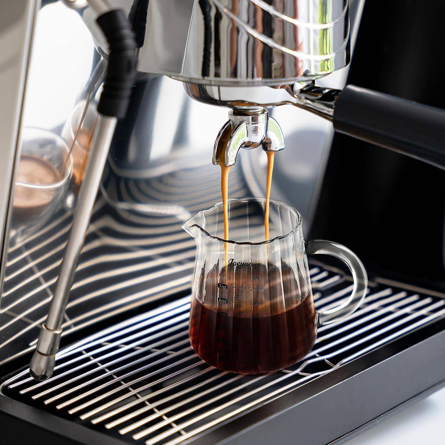 Espressomaschine, die zwei Kaffeeströme in eine Glesmessbecher auf dem Tropfblech dispensiert.