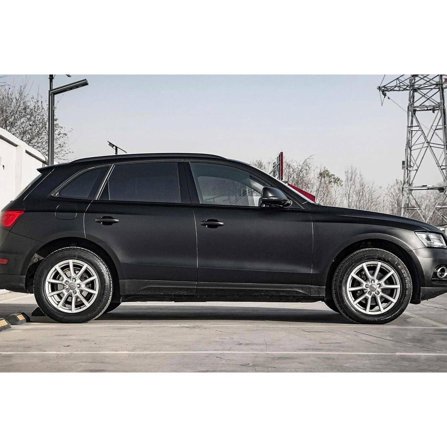 Schwarzer SUV in Seitenansicht auf einem Betonplatz geparkt, mit silbernen Leichtmetallrädern und einer industriellen Außenkulisse im Hintergrund.