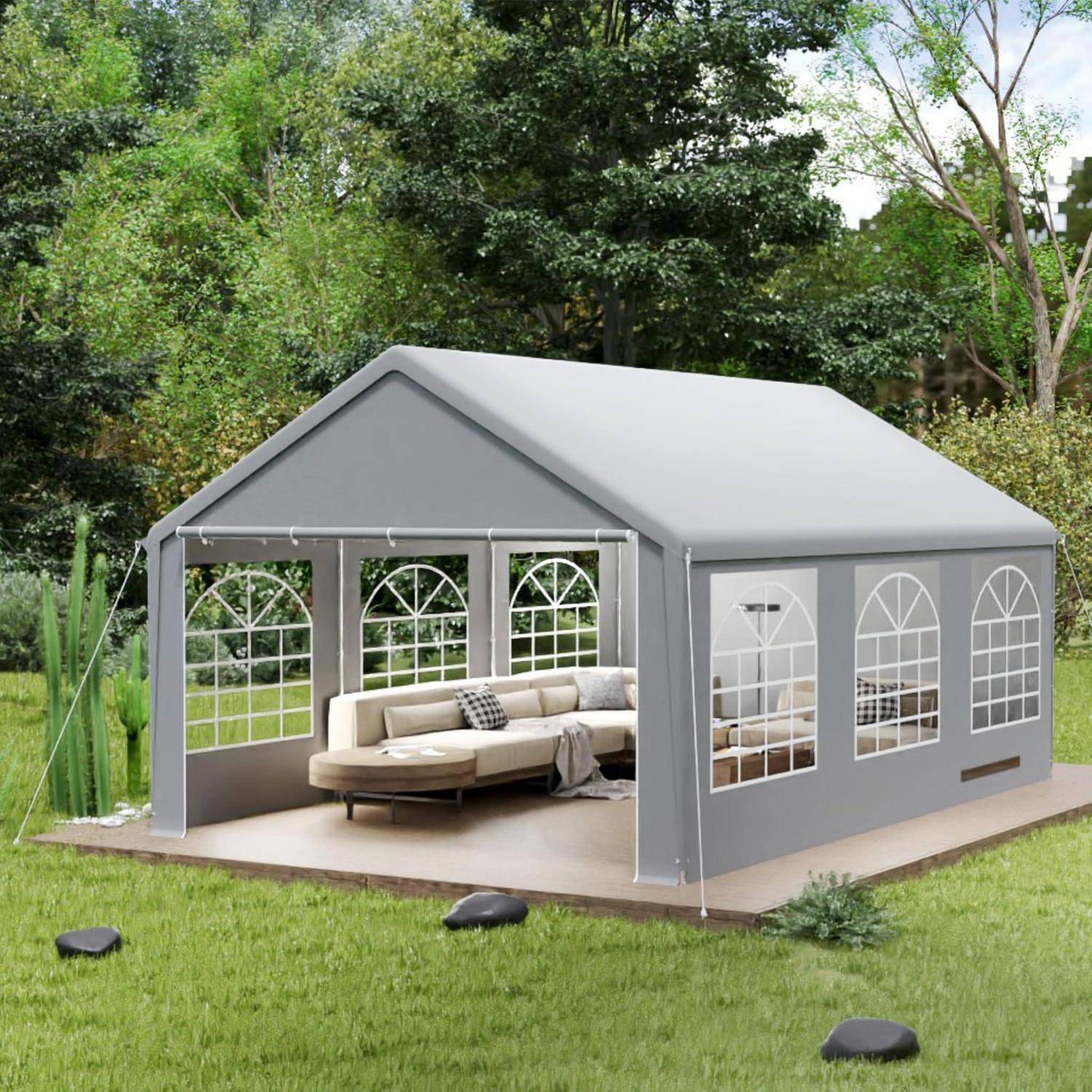 Grauweißes Außenzelt mit transparenten gewölbten Fenstern und offener Vorderseite, möbliert mit einem beigen Sofa auf einer Terrasse in einem Gartenbeet.